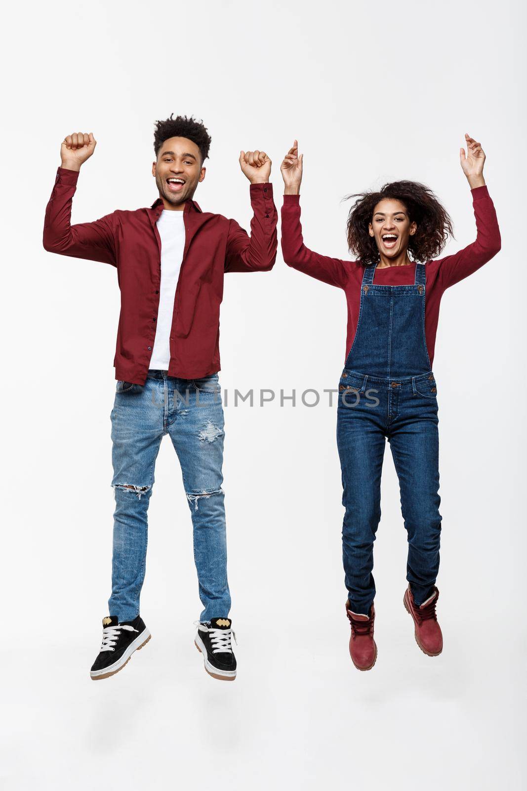 Lifestyle ,happiness and people concept: Happy young lovely African American couple jumping over bright grey background
