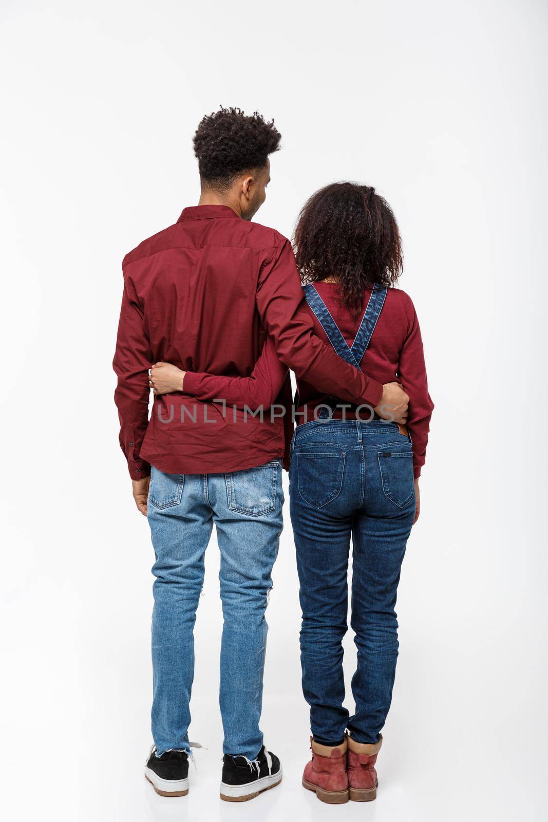 Full lenght back view of young African American couple hugging together isolated on white background by Benzoix