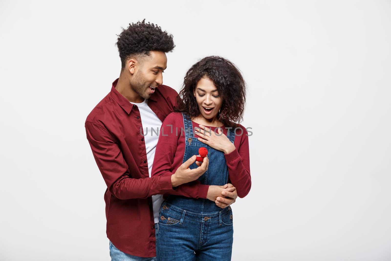 Young handsome african american man surprisingly ask her girlfriend for proposal. by Benzoix