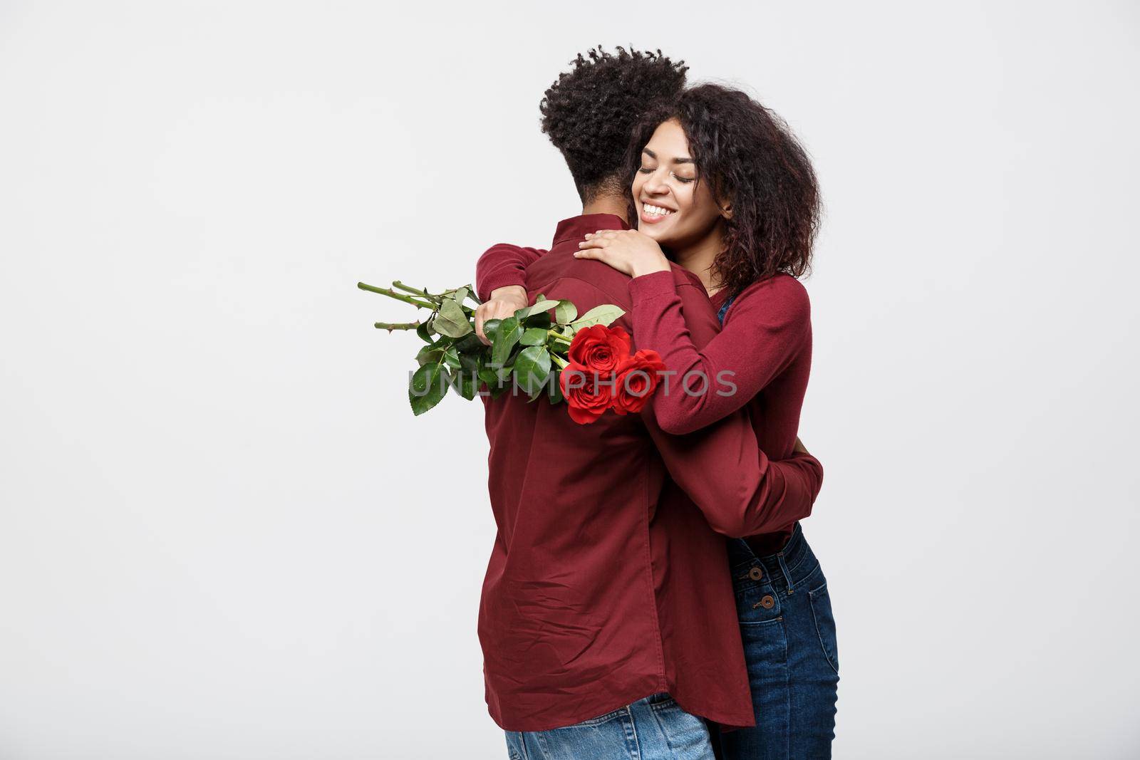 Couple Concept - Young african american couple huging each other and holding romantic red rose. by Benzoix