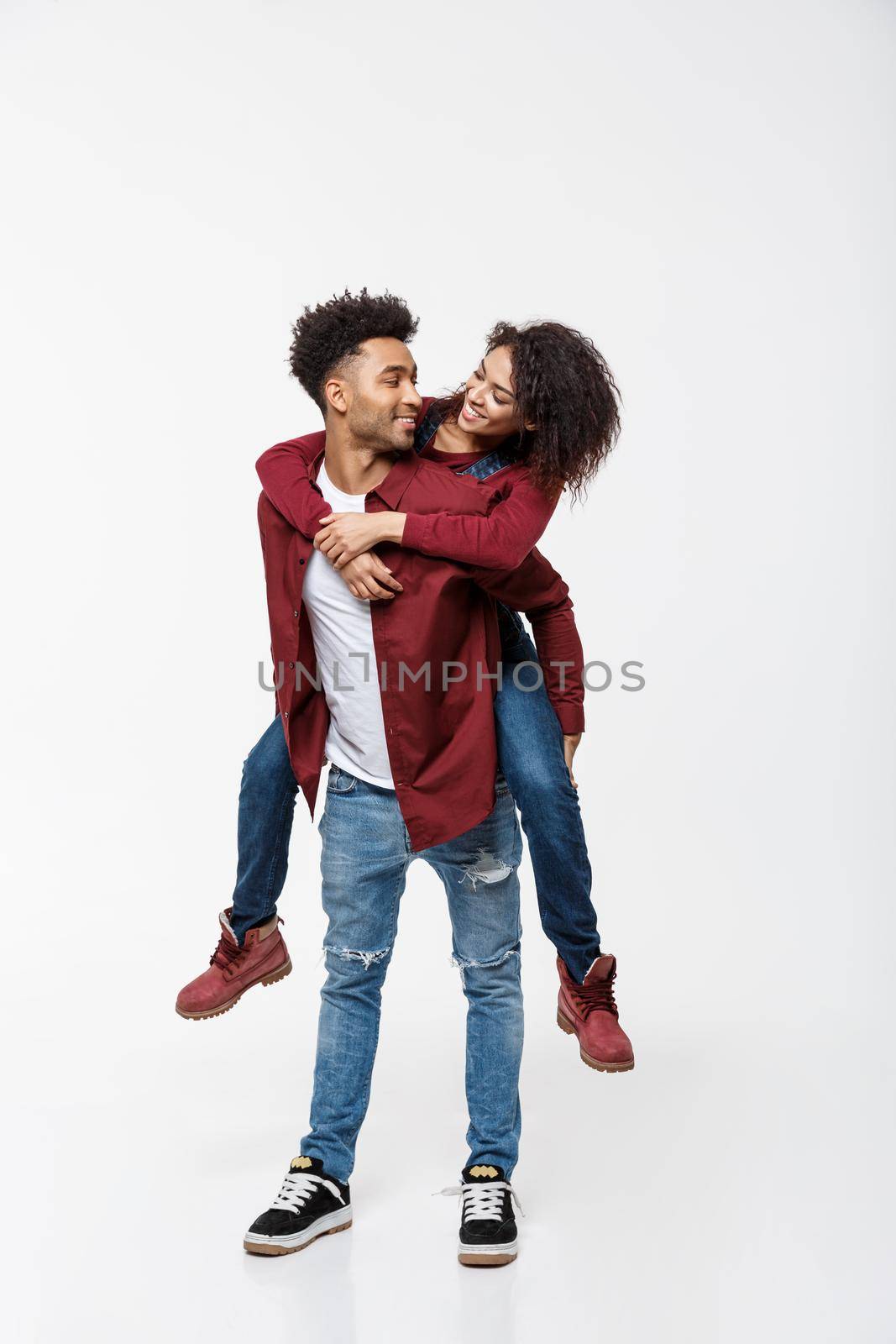 Full length young attractive african american lady riding back on her boyfriend back and enjoy playing to each other. by Benzoix