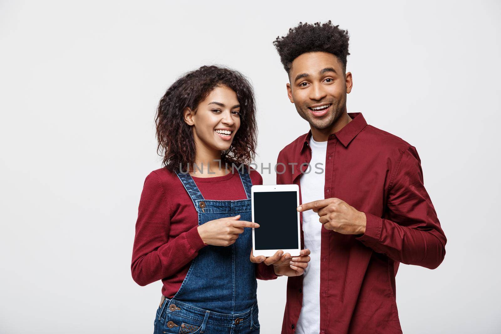 Portrait of African American couple holding table with happy expression on white background by Benzoix