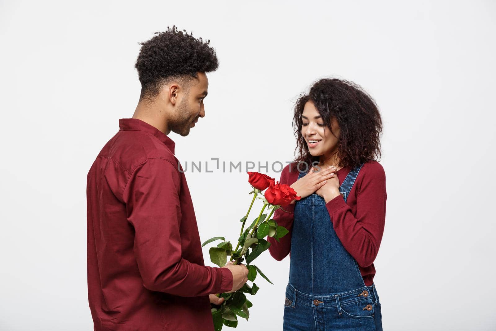 Beautiful elegant couple is hugging and smiling, on gray background. Girl is holding roses by Benzoix