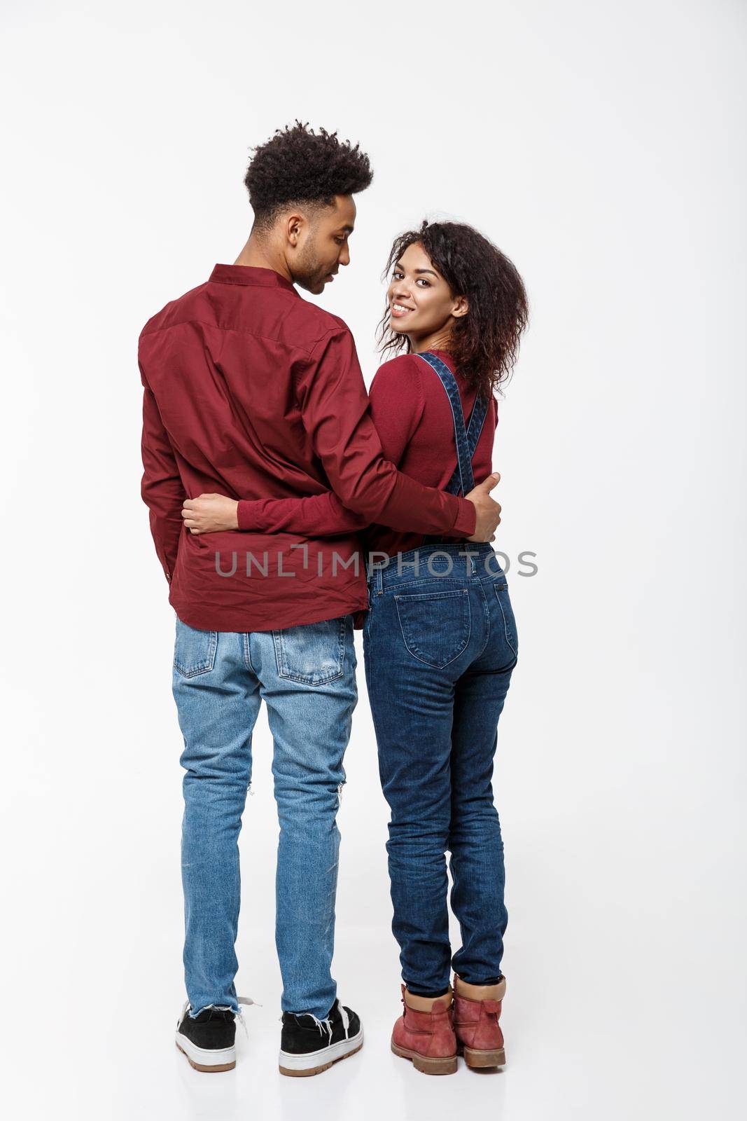 Full lenght back view of young African American couple hugging together isolated on white background.