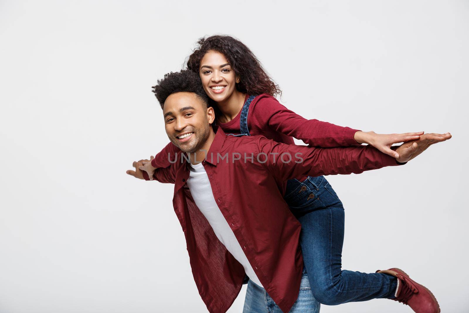 Close-up young african american couple riding back and playing like plane. by Benzoix