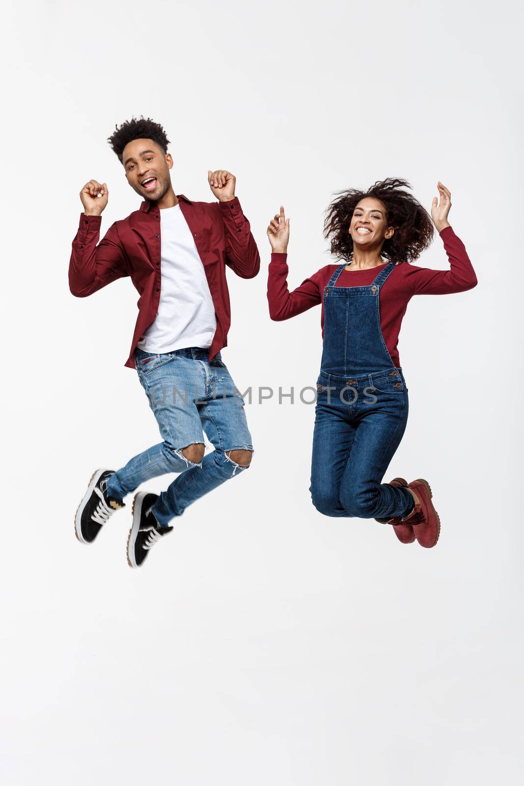 Lifestyle ,happiness and people concept: Happy young lovely African American couple jumping over bright grey background. by Benzoix