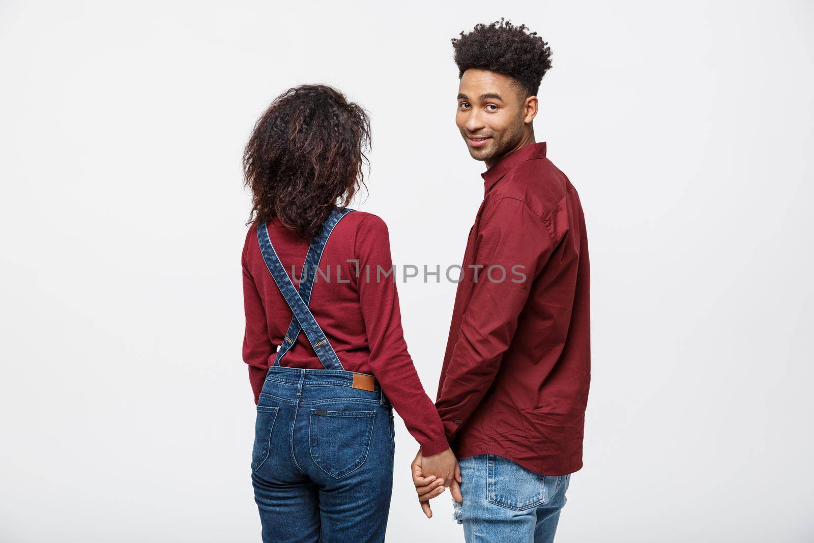 Portrait rear view of young afro american couple holding hands isolated on white background by Benzoix