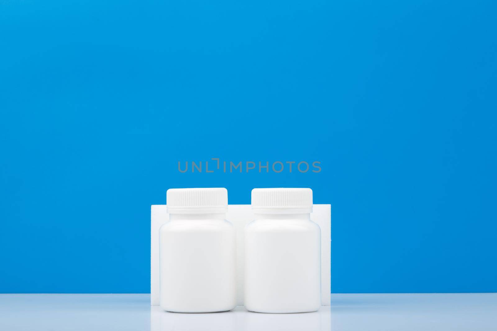 Two white medication bottles against blue background with copy space.  by Senorina_Irina
