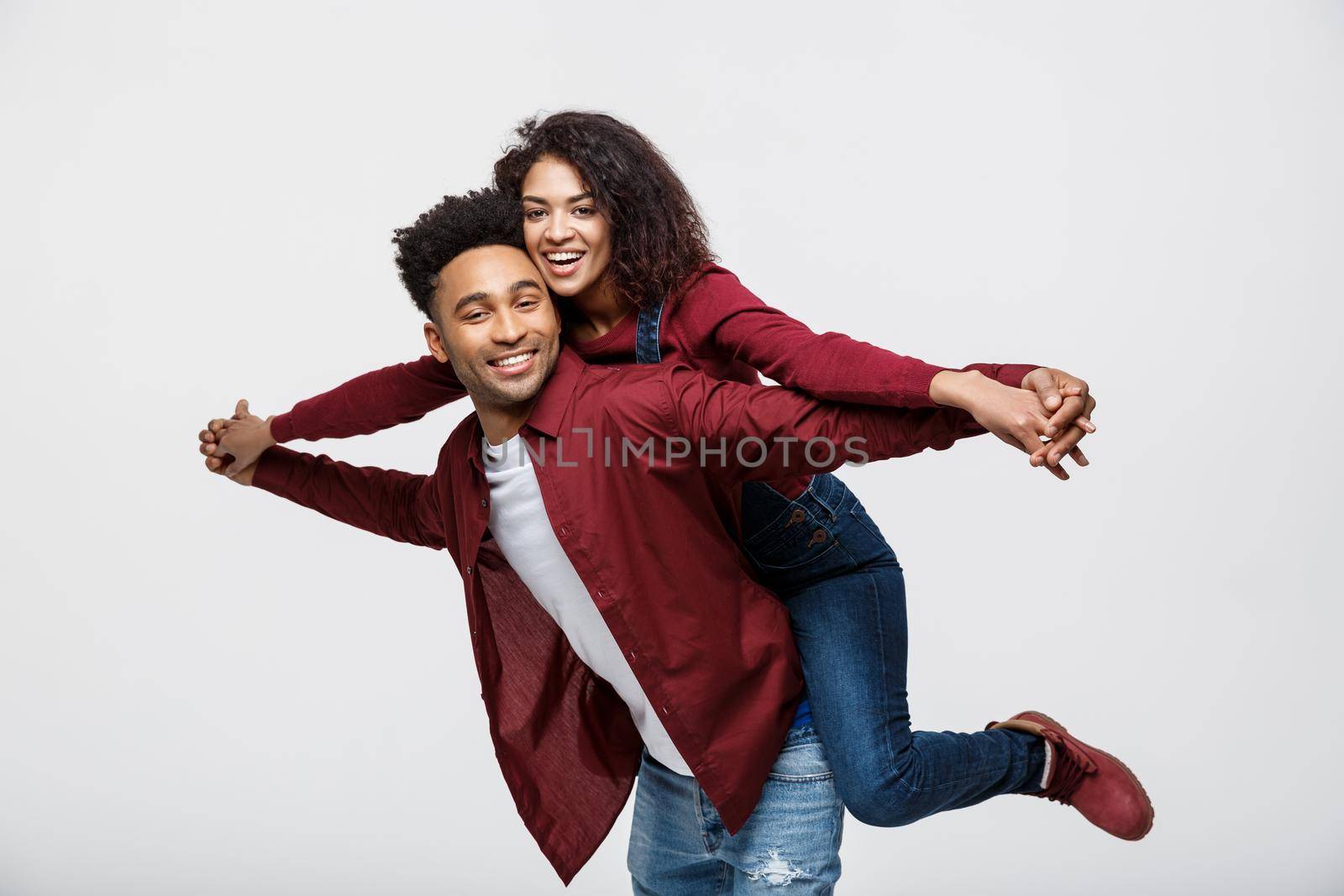 Close-up young african american couple riding back and playing like plane. by Benzoix