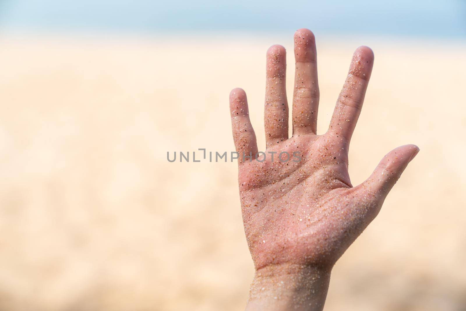 Hands stained with sand, beach and sea background.
