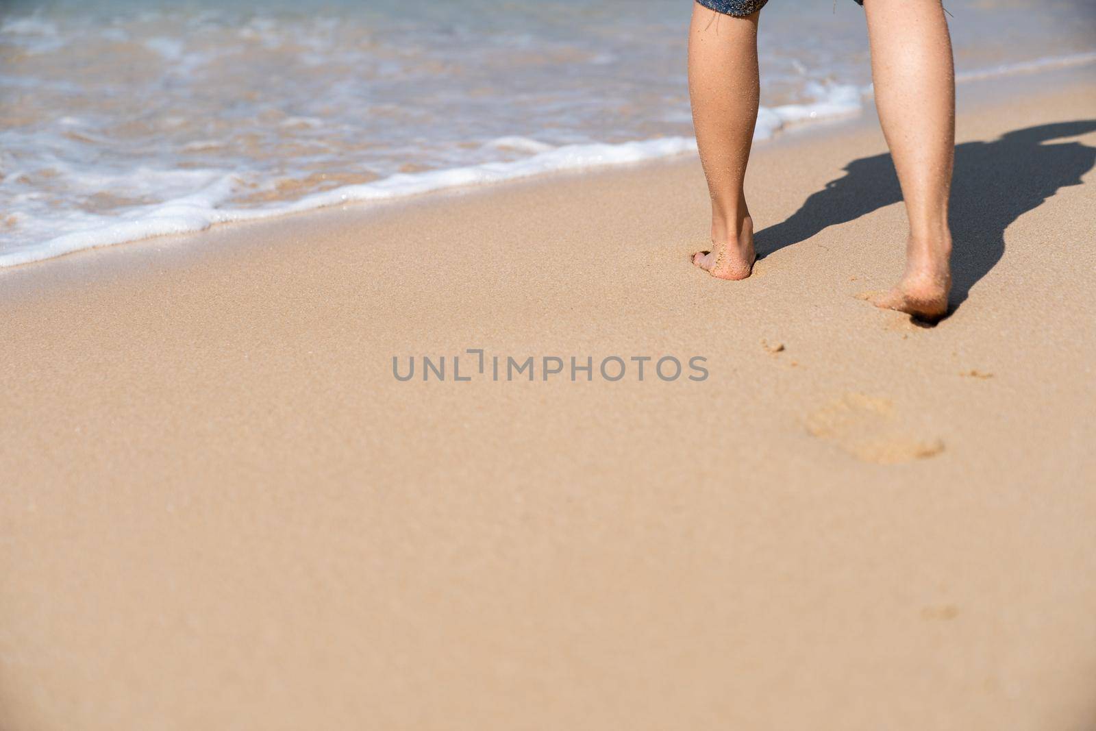 Footprints in the sand on the beach. Woman walking to the sea.