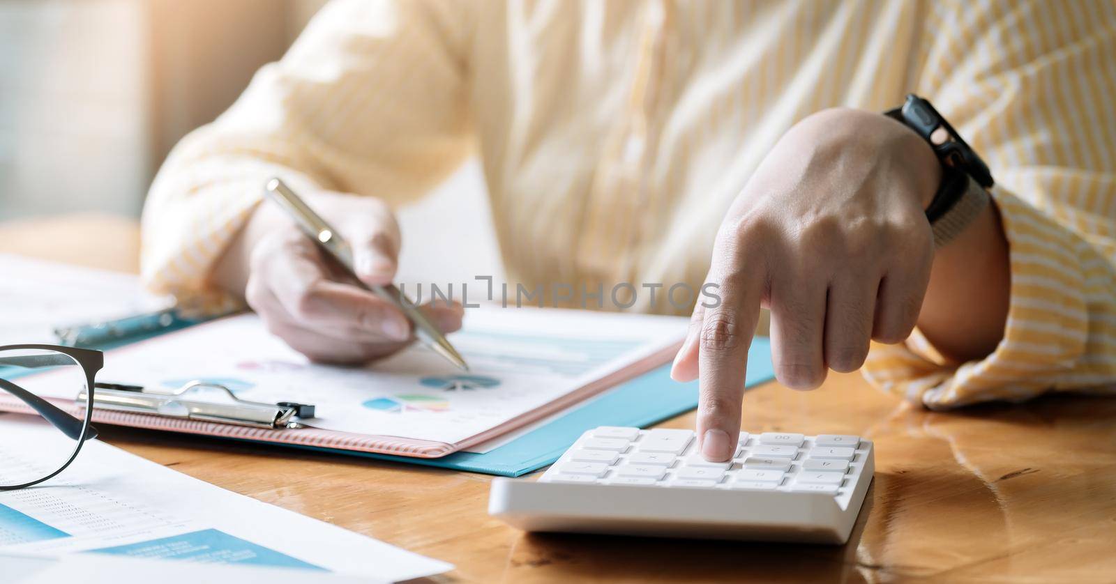 Accountant or bookkeeper working on desk using calculator, accounting finance concept