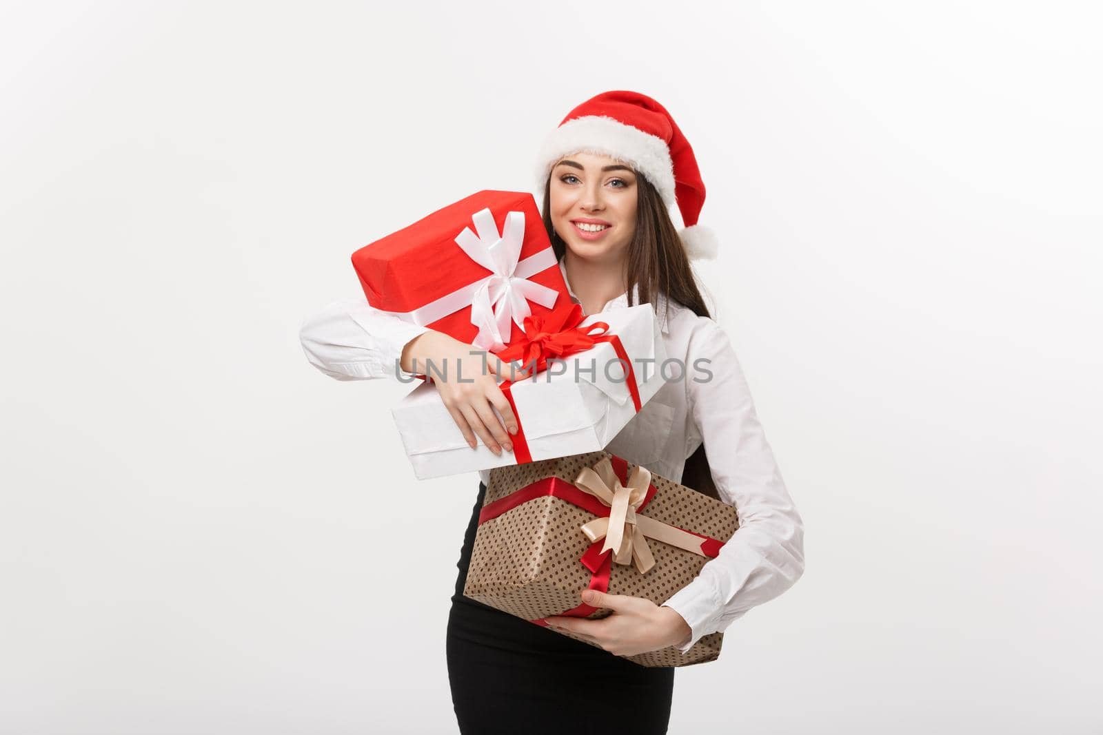 Business Concept - Beautiful young caucasian business woman with santa hat holding a lot of christmas gift boxes with copy space on side. by Benzoix