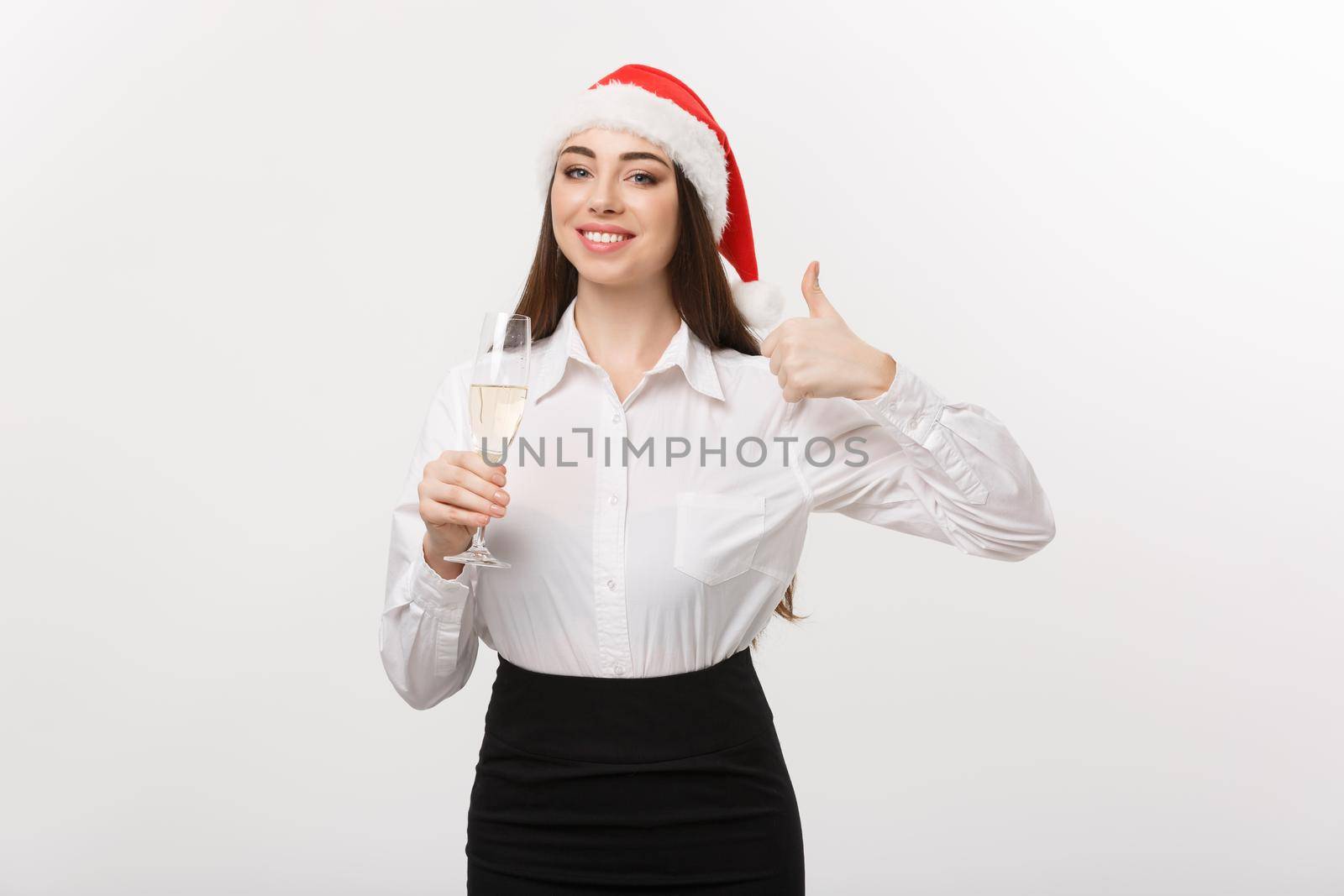Christmas Celebration - Young beautiful business woman celebrating christmas with glass of champagne and showing thumb up. by Benzoix
