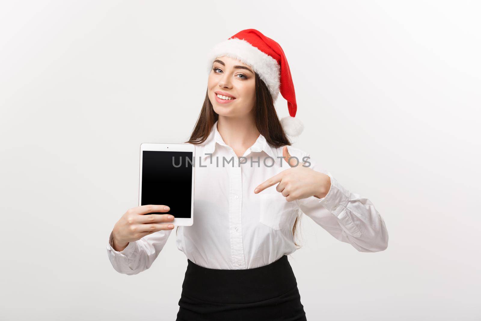 Business Concept - young caucasian business woman in Christmas theme showing and pointing to digital tablet.