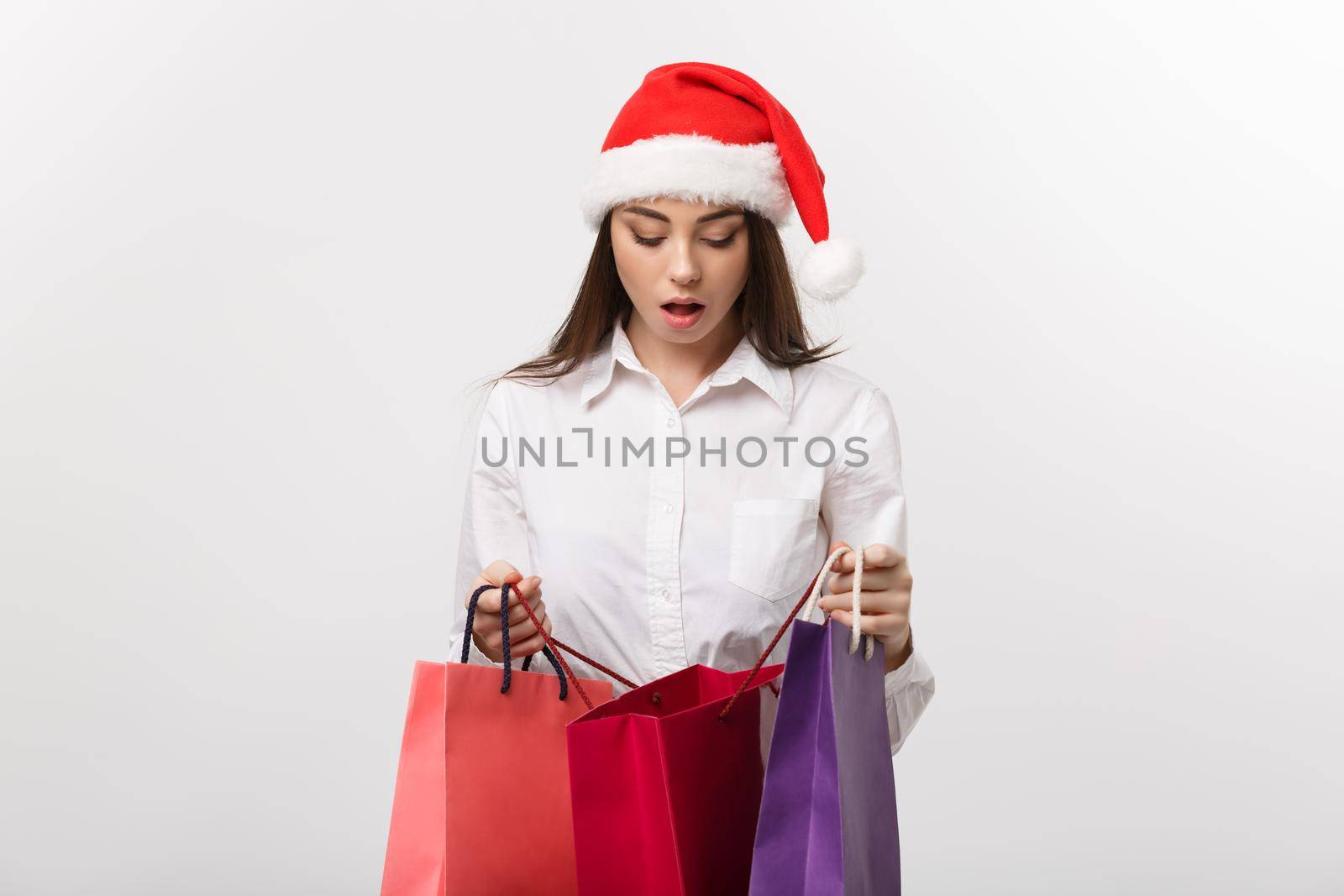 Christmas Concept - beautiful caucasian business woman shocking with gift inside shopping bag.