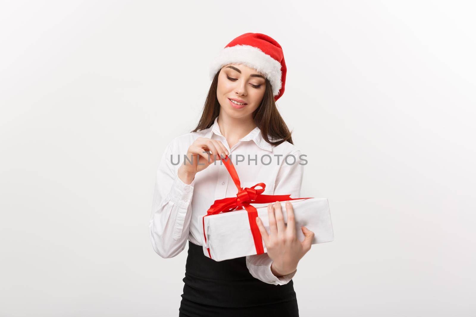 Christmas Concept - young happy caucasian business woman with santa hat smiling while open gift box with copy space on side.