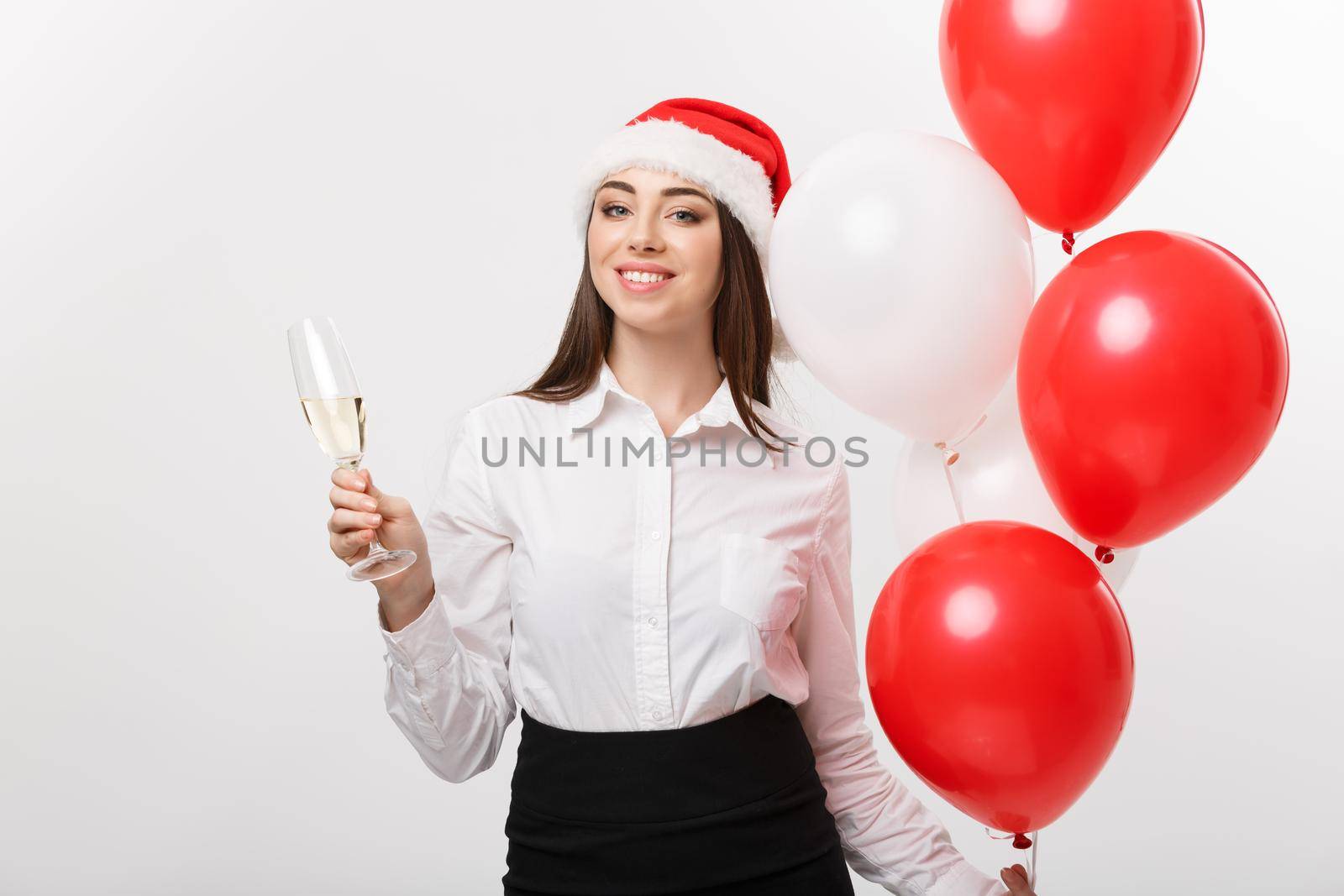 Christmas Celebration - Young beautiful business woman celebrating christmas with glass of champagne and confetti background. by Benzoix