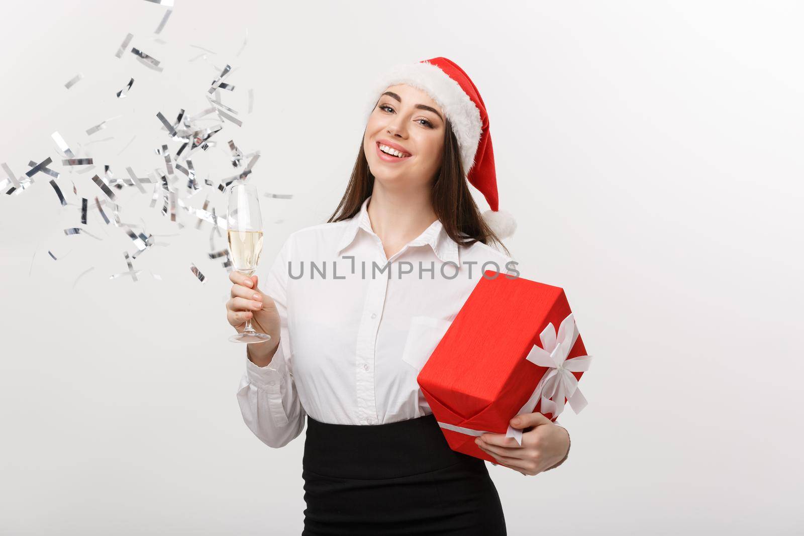 Christmas Celebration - Young beautiful business woman celebrating christmas with glass of champagne and confetti background. by Benzoix