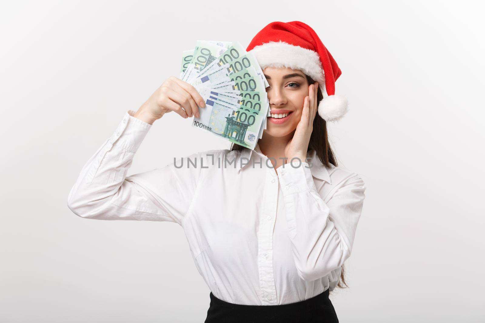 Christmas and finance concept - Young business woman showing money closing her face with surprise expression.