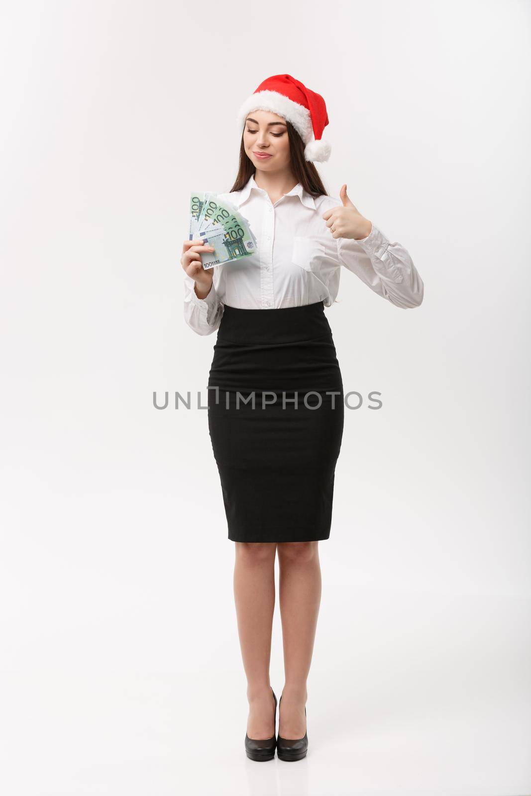 Christmas and finance concept - Young business woman showing money and thumb up in front of camera.