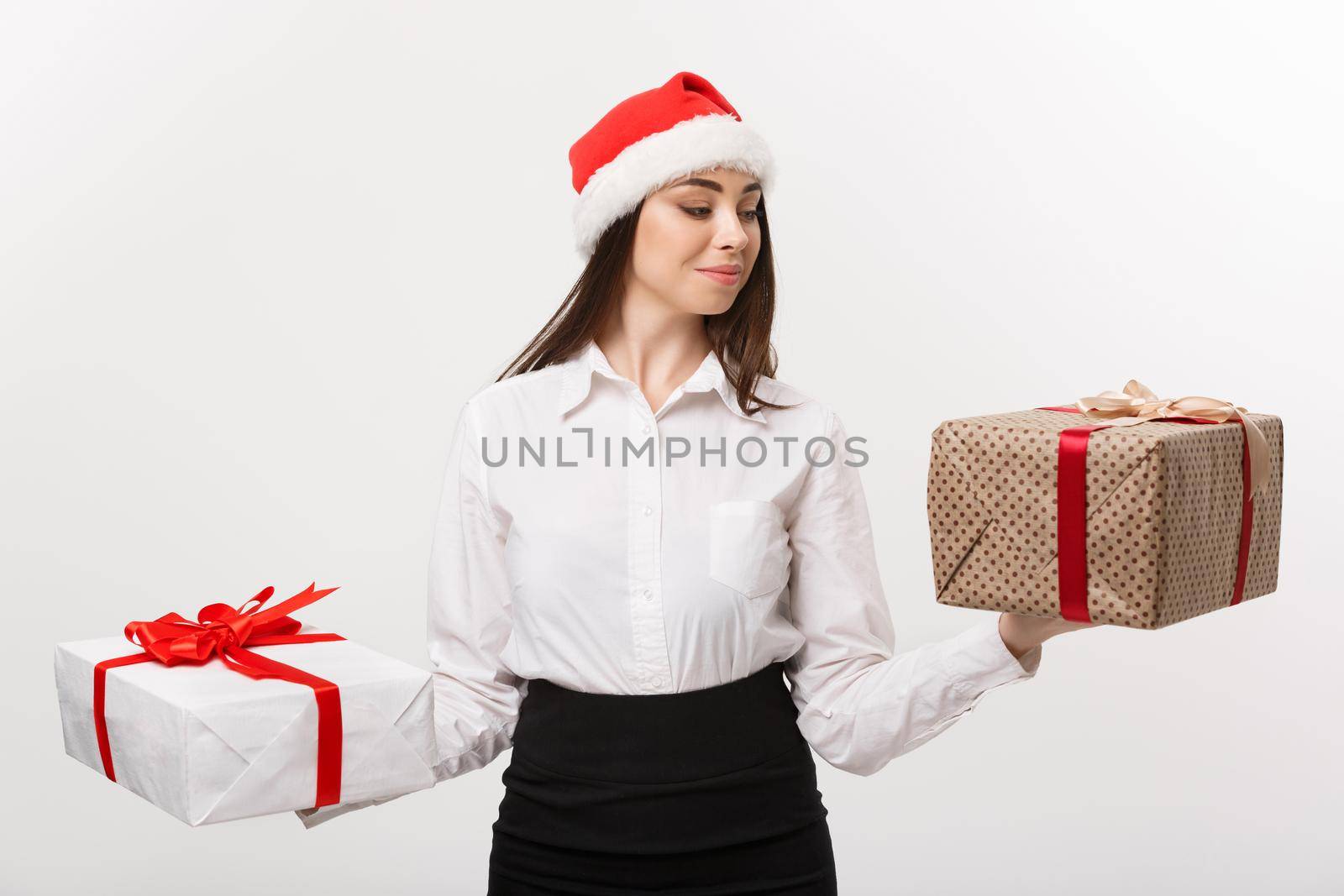 Christmas Concept - young happy caucasian business woman with santa hat choosing gift boxs with copy space on side. by Benzoix