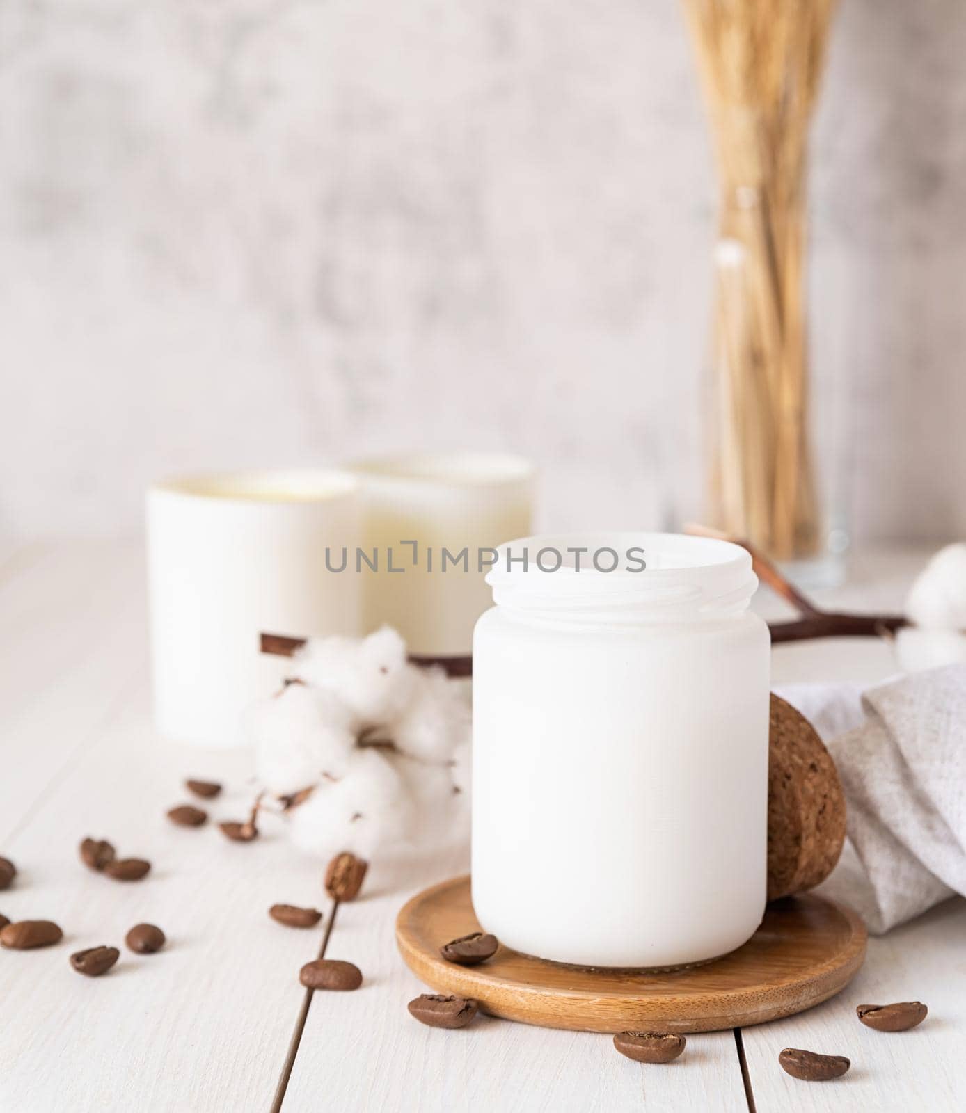 Home decoration and interior. Beautiful burning candles with cotton flowers and coffee beans on white wooden background