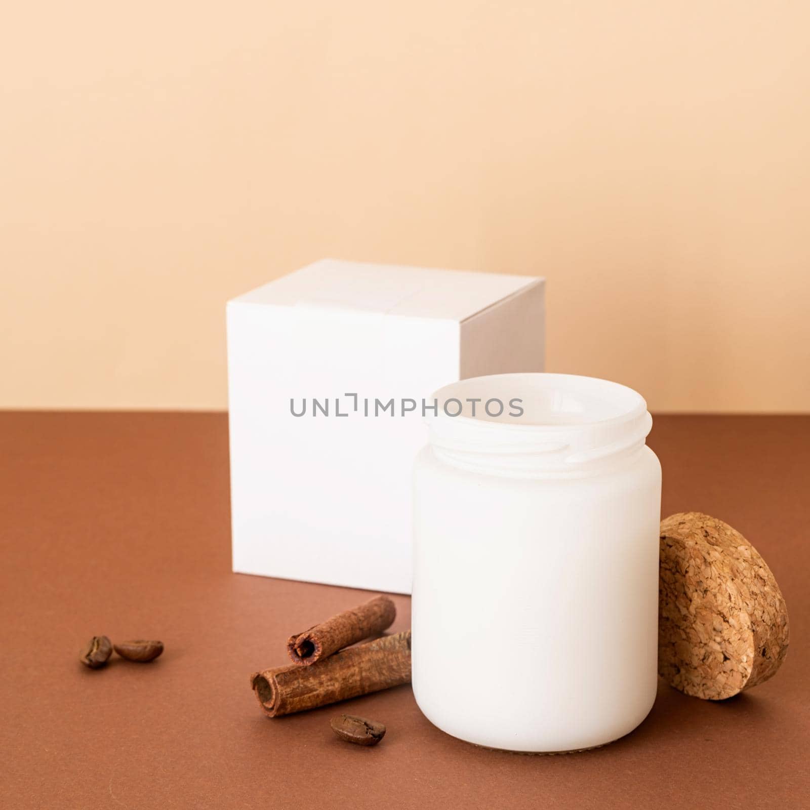 Beautiful white candle with cinnamon sticks on brown solid background by Desperada