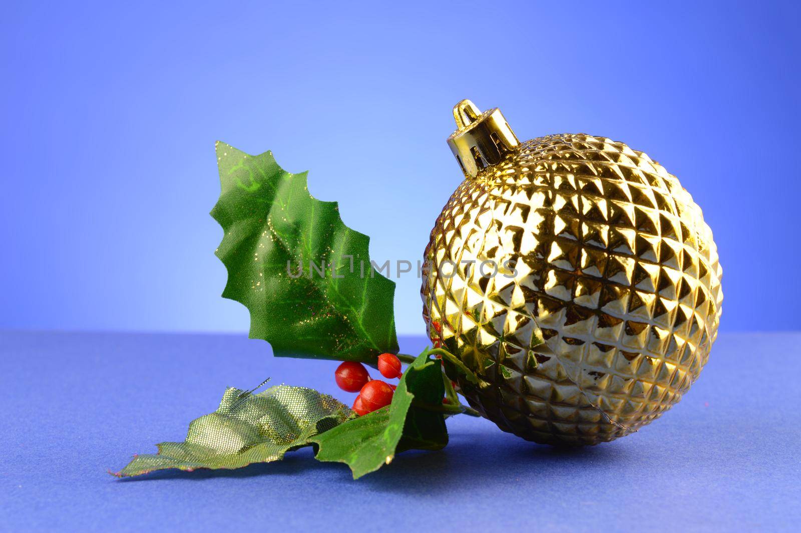 A festive golden bauble with some holly for the Christmas season.