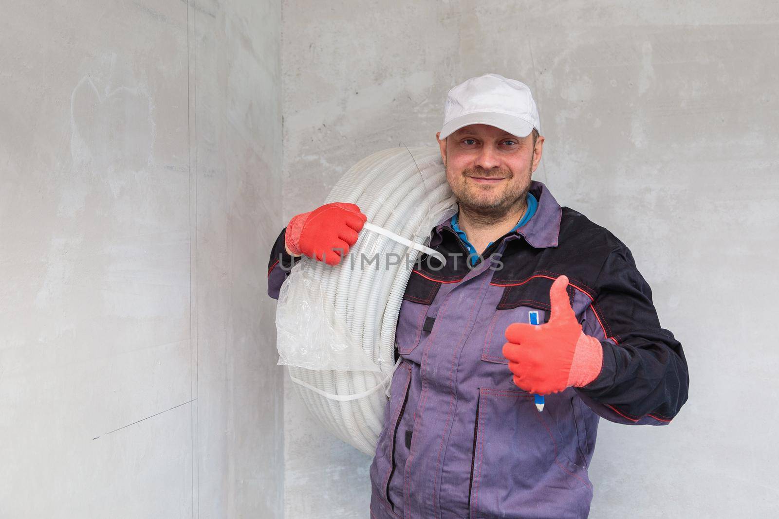 Electrician with a reel of corrugated cable for outlets. Close-up