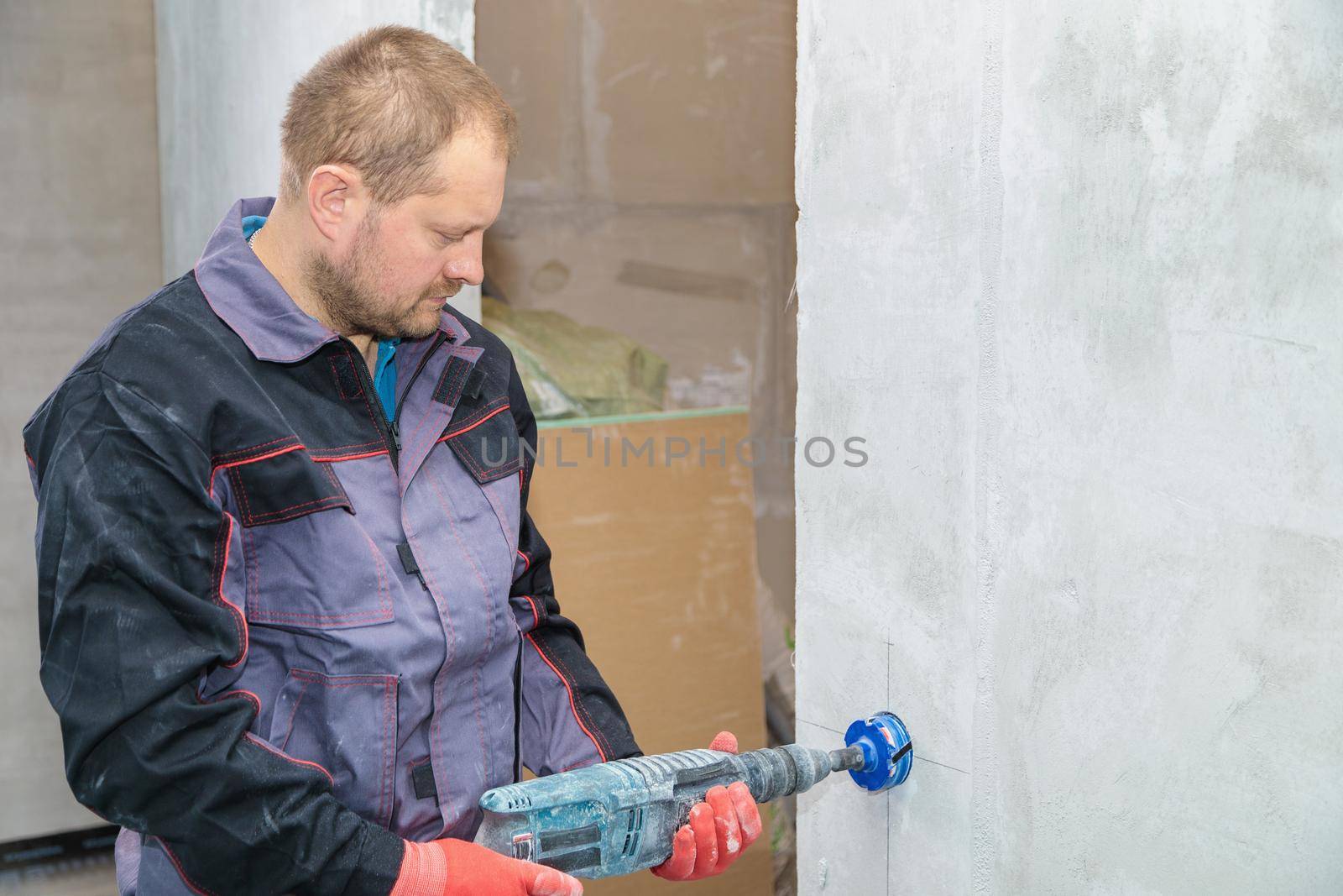 An electrician drills holes for sockets with a diamond core bit by Yurich32