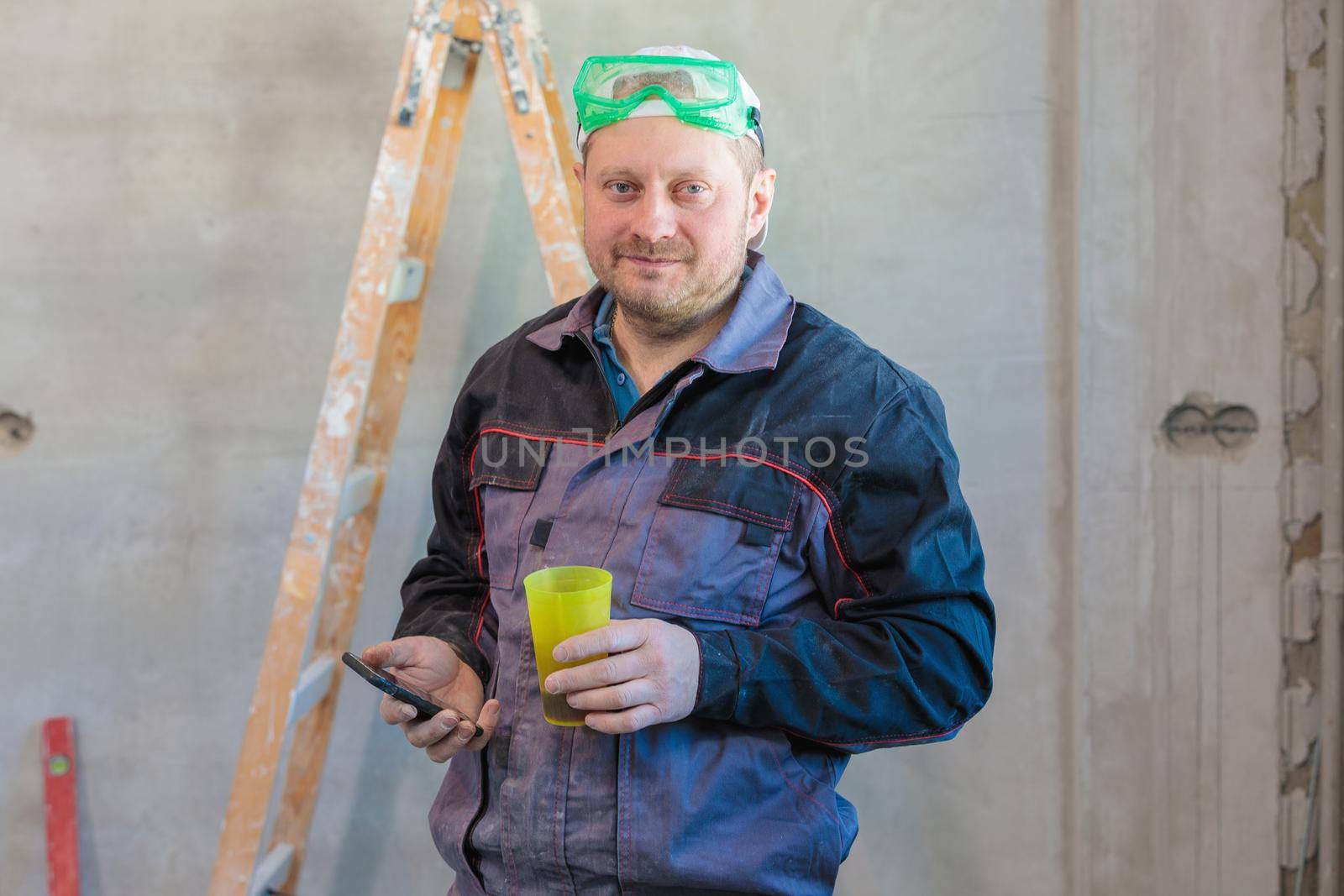 An electrician drinks tea during his lunch break at the enterprise. by Yurich32