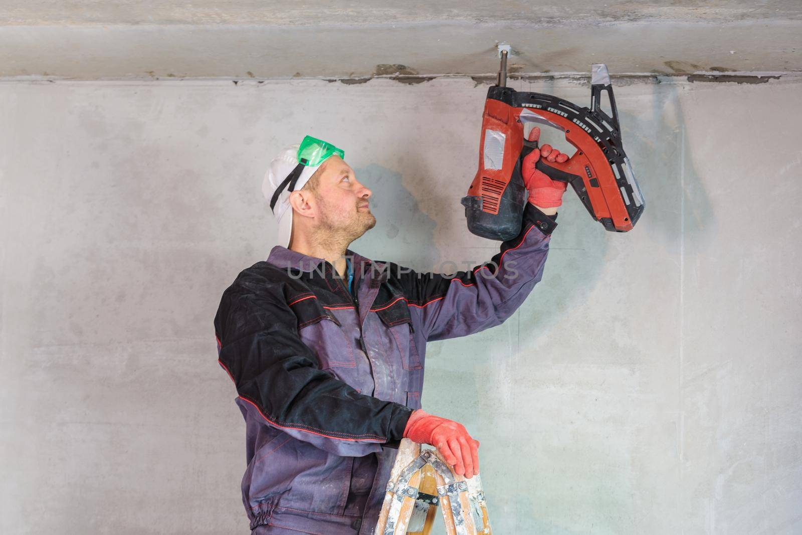 An electrician nails a wire holder to the ceiling. Repair of apartments. Close-up