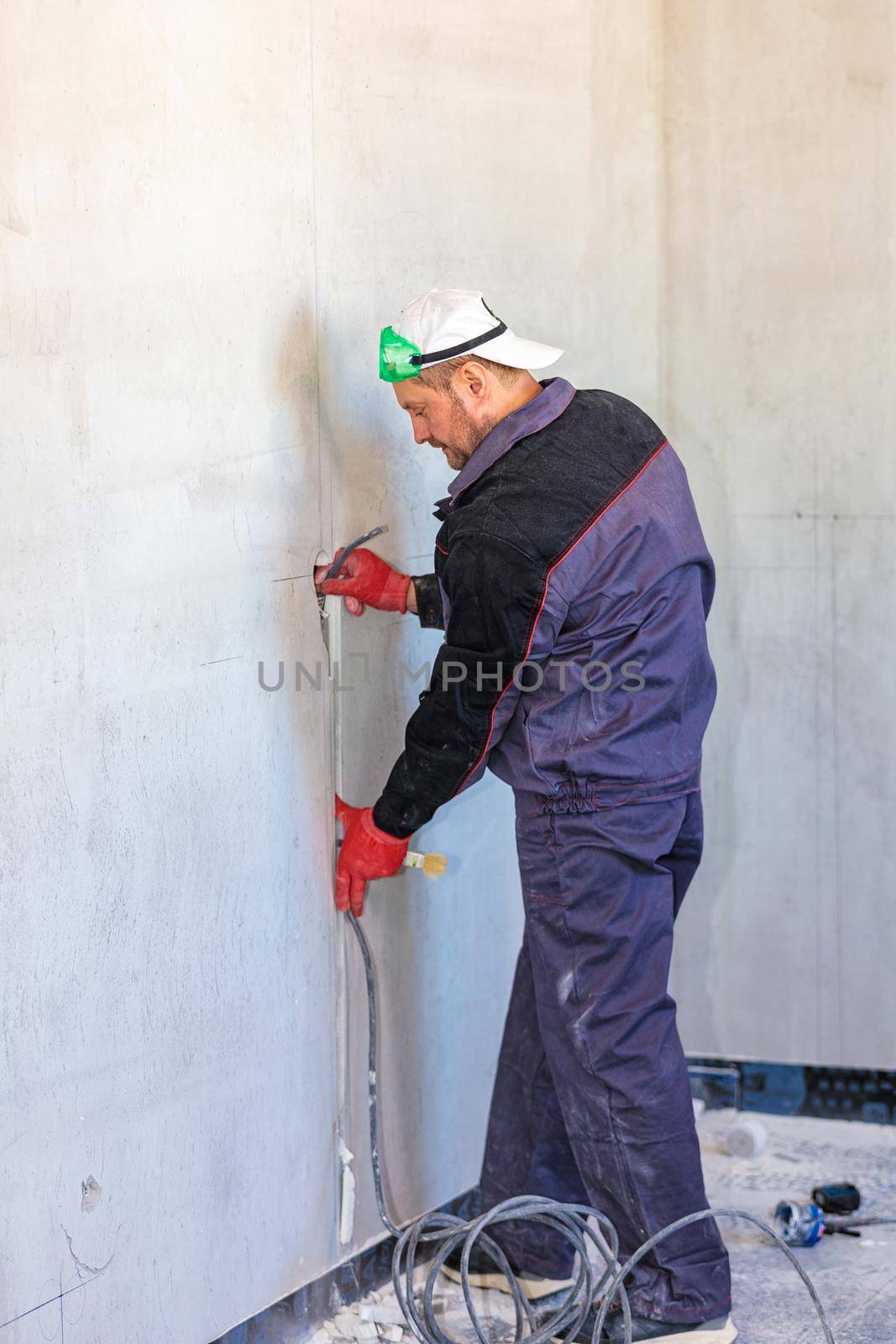 An electrician is laying a cable in an electrical ditch. Apartment renovation. Close-up