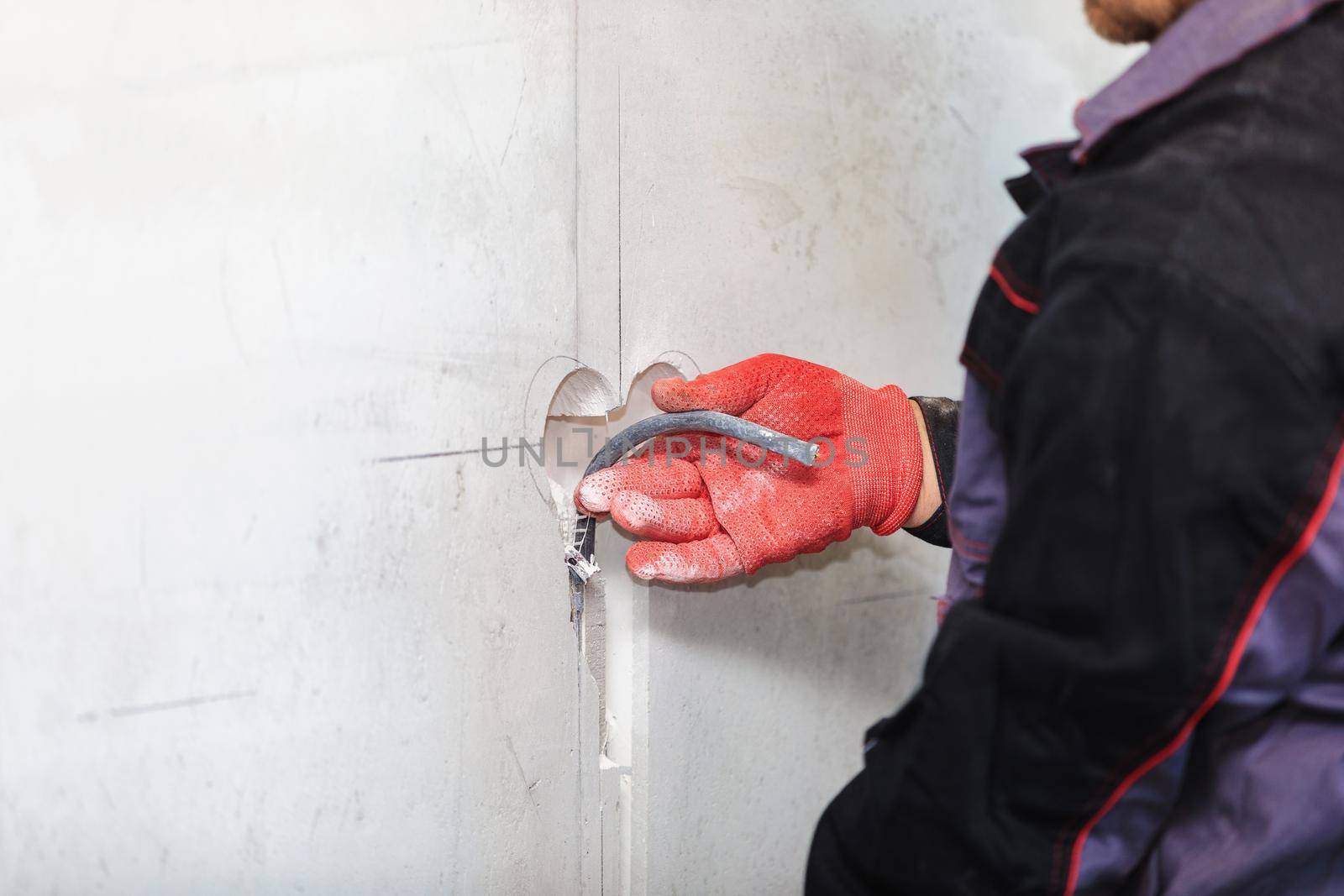 An electrician is laying a cable in an electrical ditch. Apartment renovation. Close-up