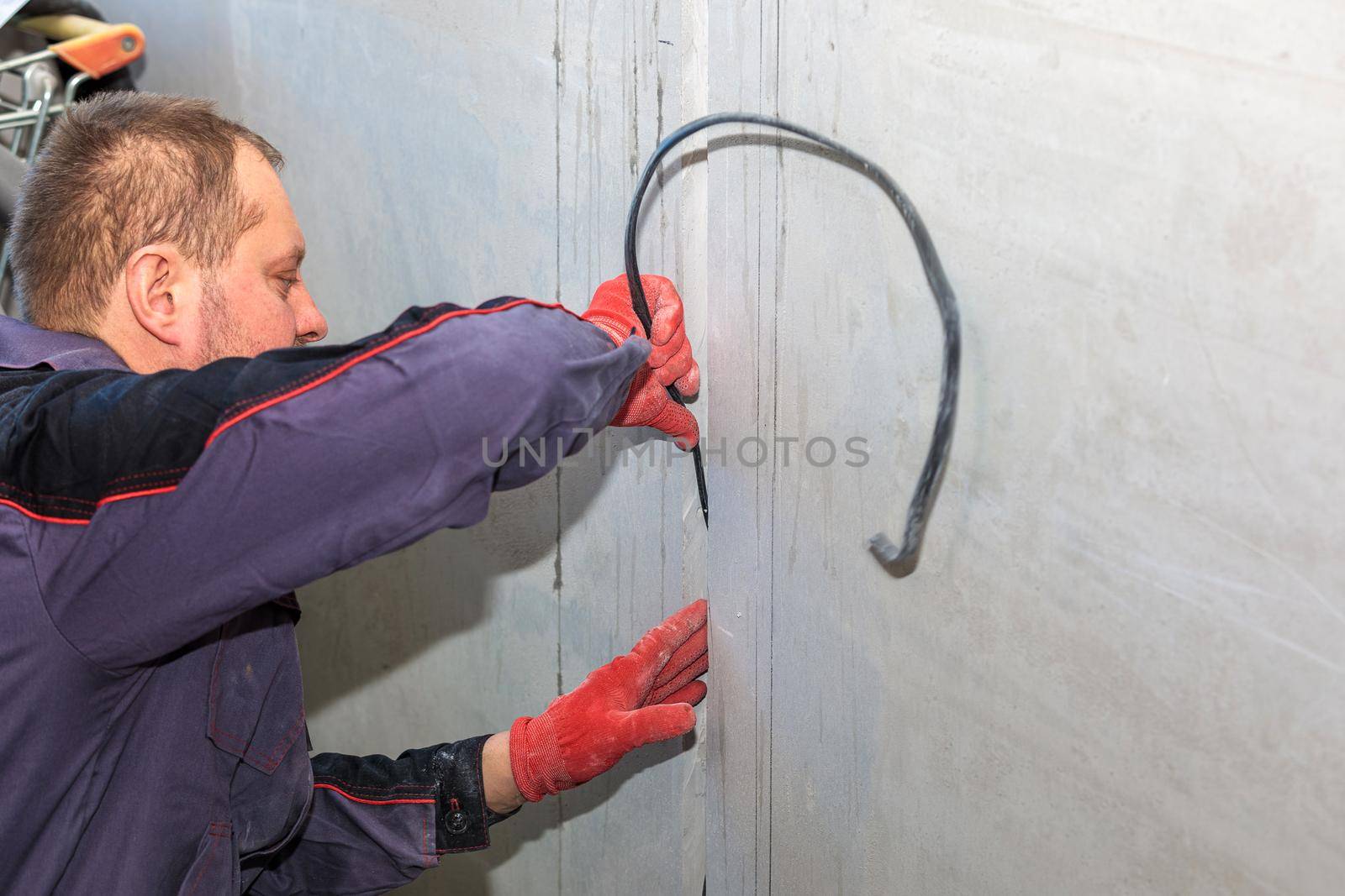 An electrician is laying a cable in an electrical ditch. Apartment renovation. Close-up