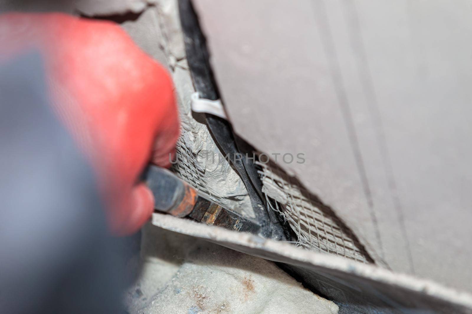 An electrician is laying a cable in an electrical ditch. Apartment renovation. Close-up