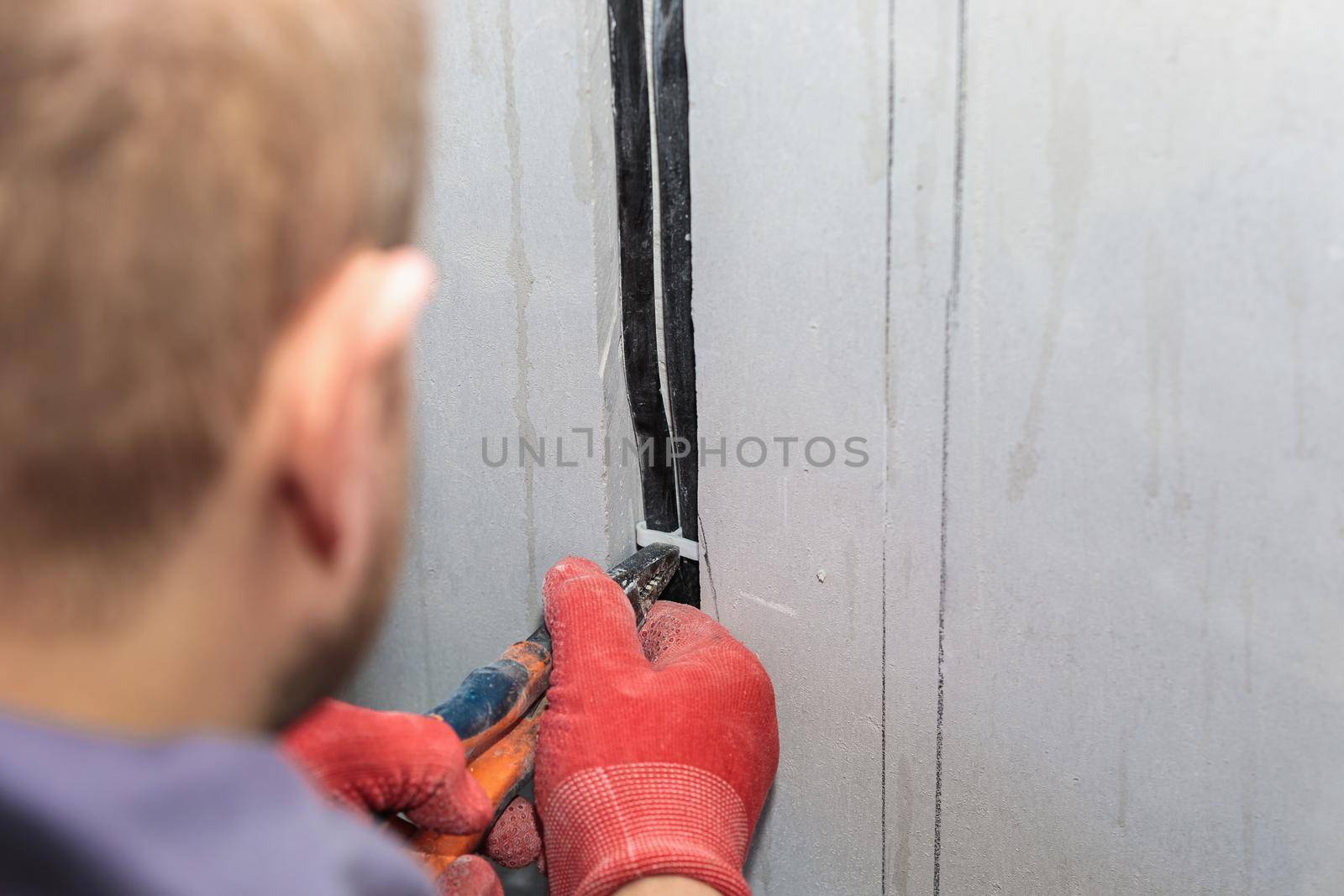 An electrician is laying a cable in an electrical ditch. Apartment renovation. Close-up