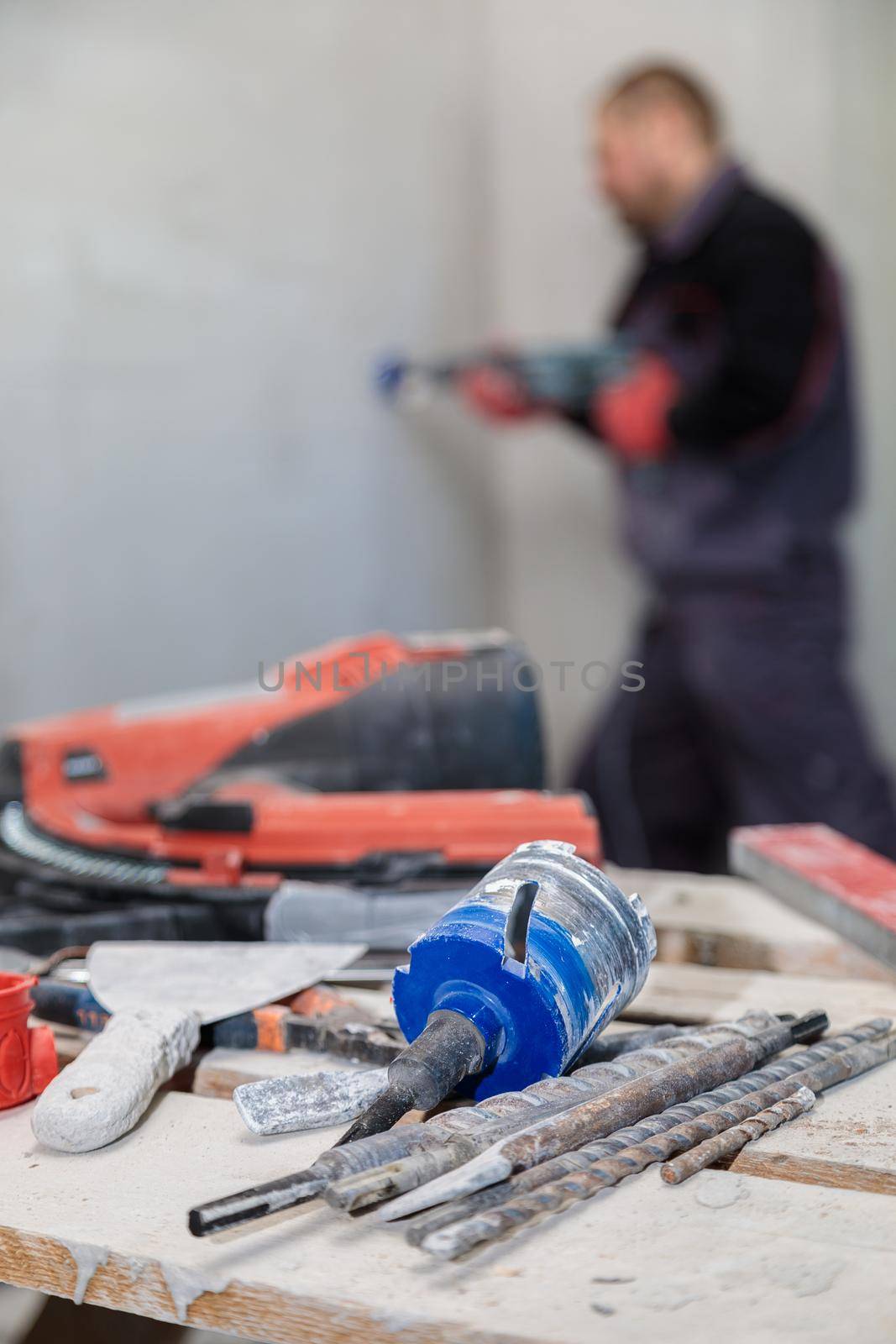 An electrician drills holes for sockets with a diamond core bit. Close-up