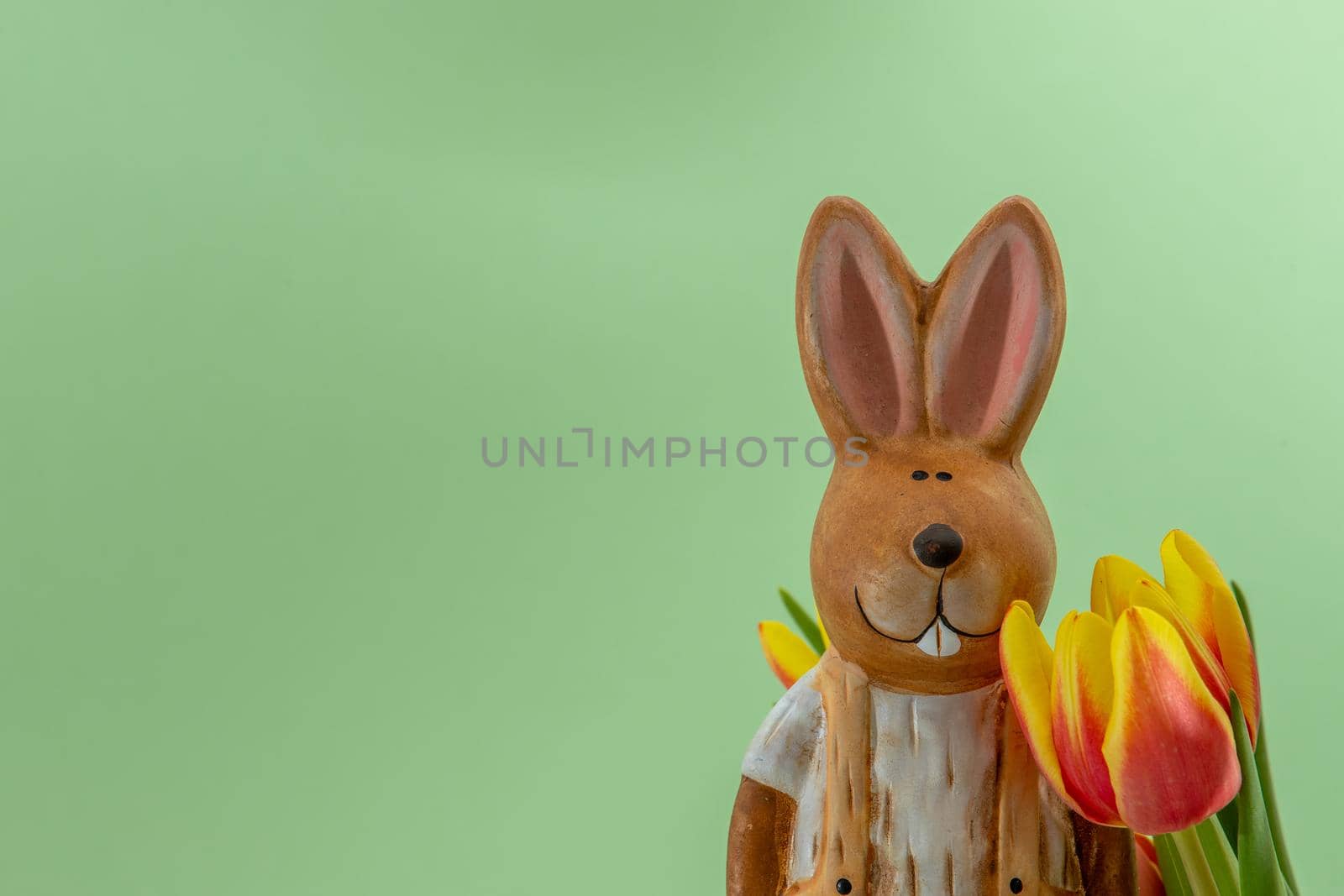 Porcelain easter bunny with yellow red tulip flowers against a light green background