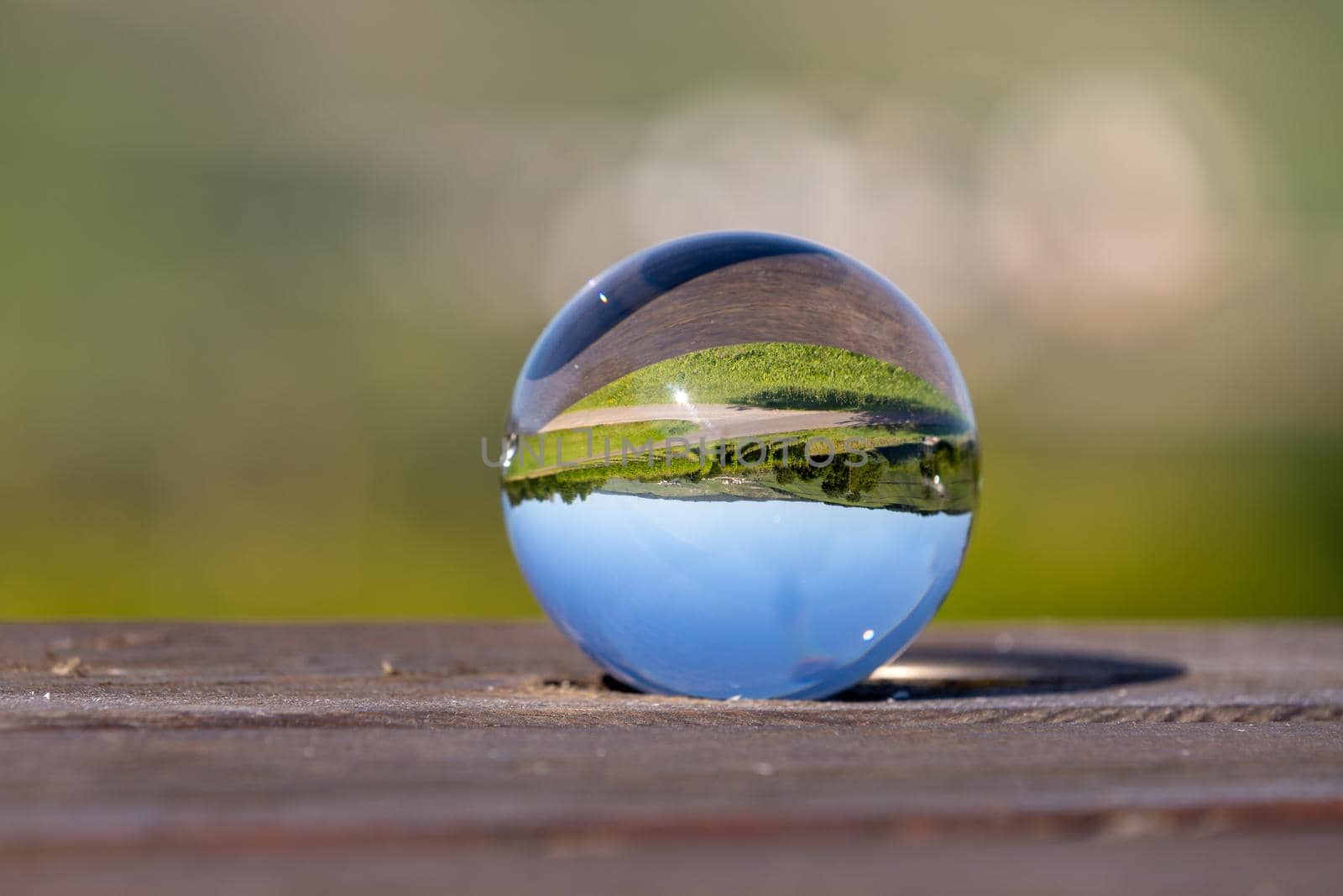 Crystal ball on wooden table shows landscape of river Moselle