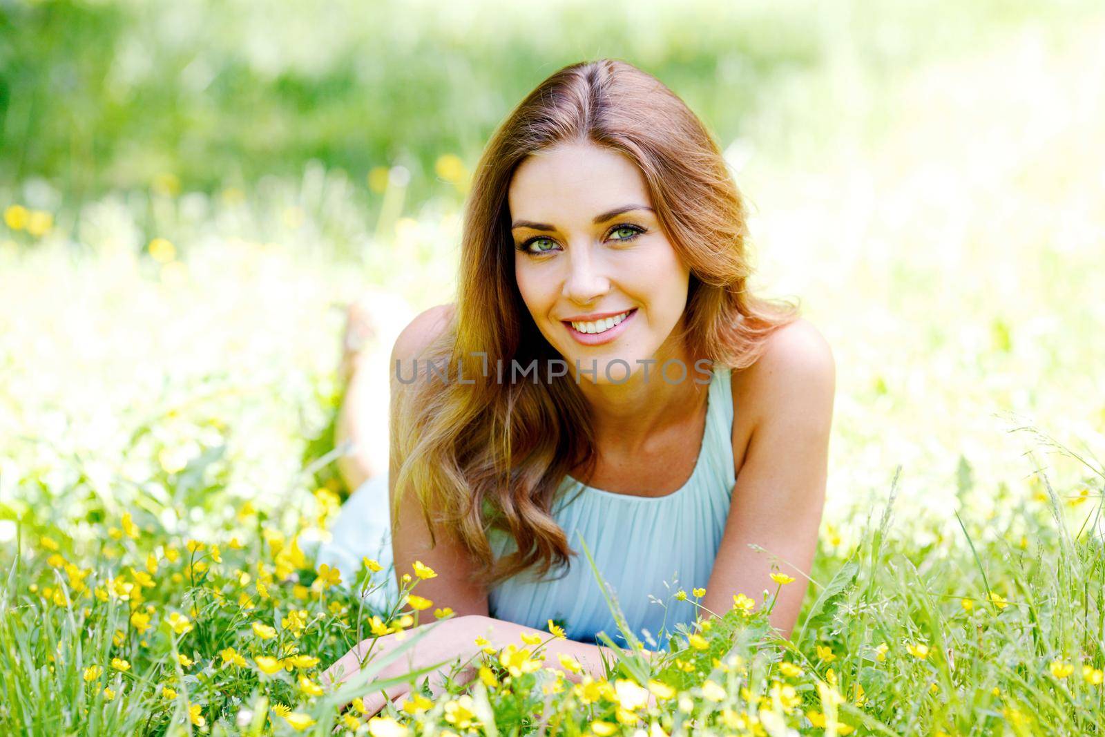 Woman in blue dress lying on grass by Yellowj