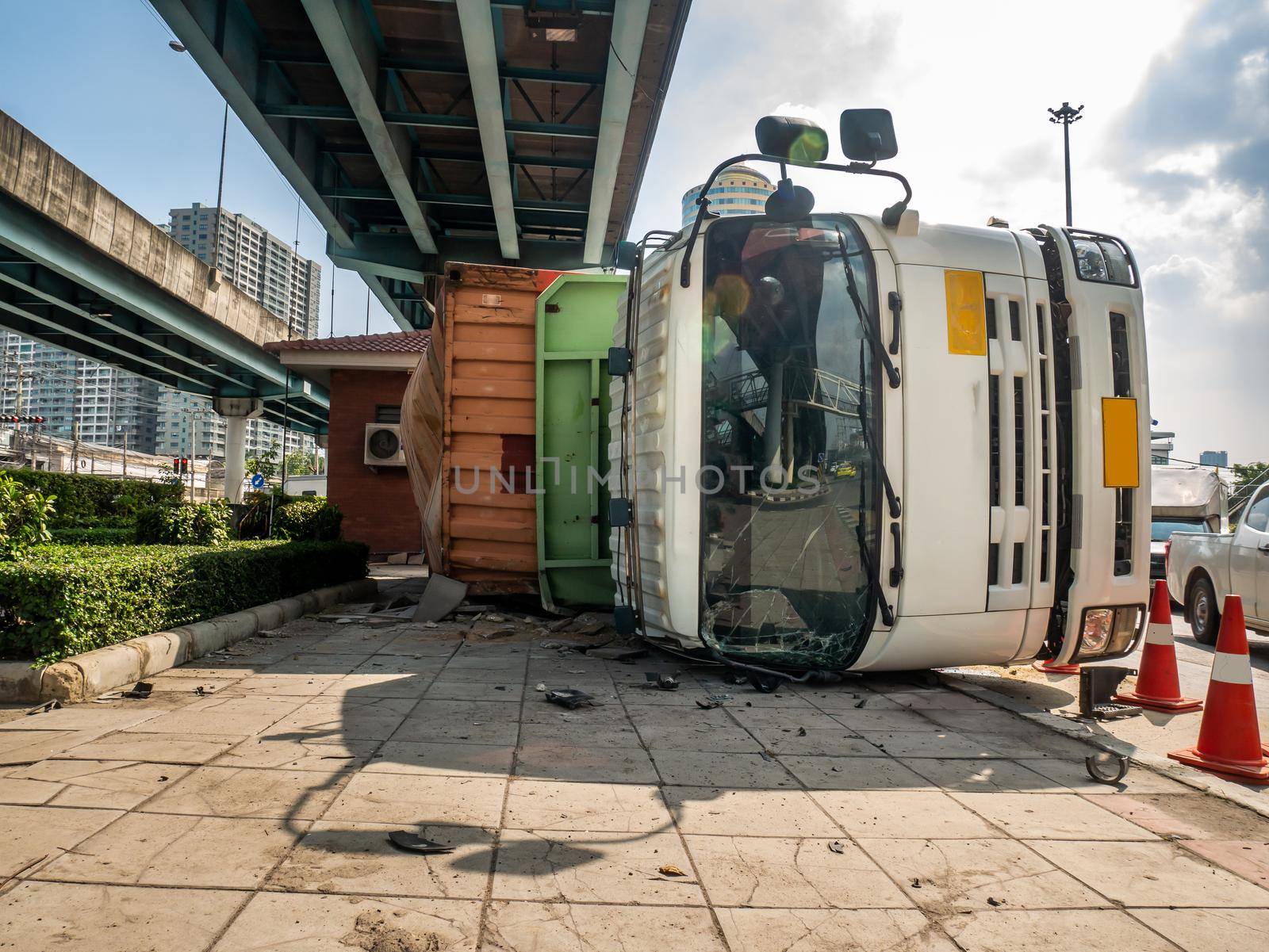 A truck carrying a container overturned on a road under a bridge over an intersection.