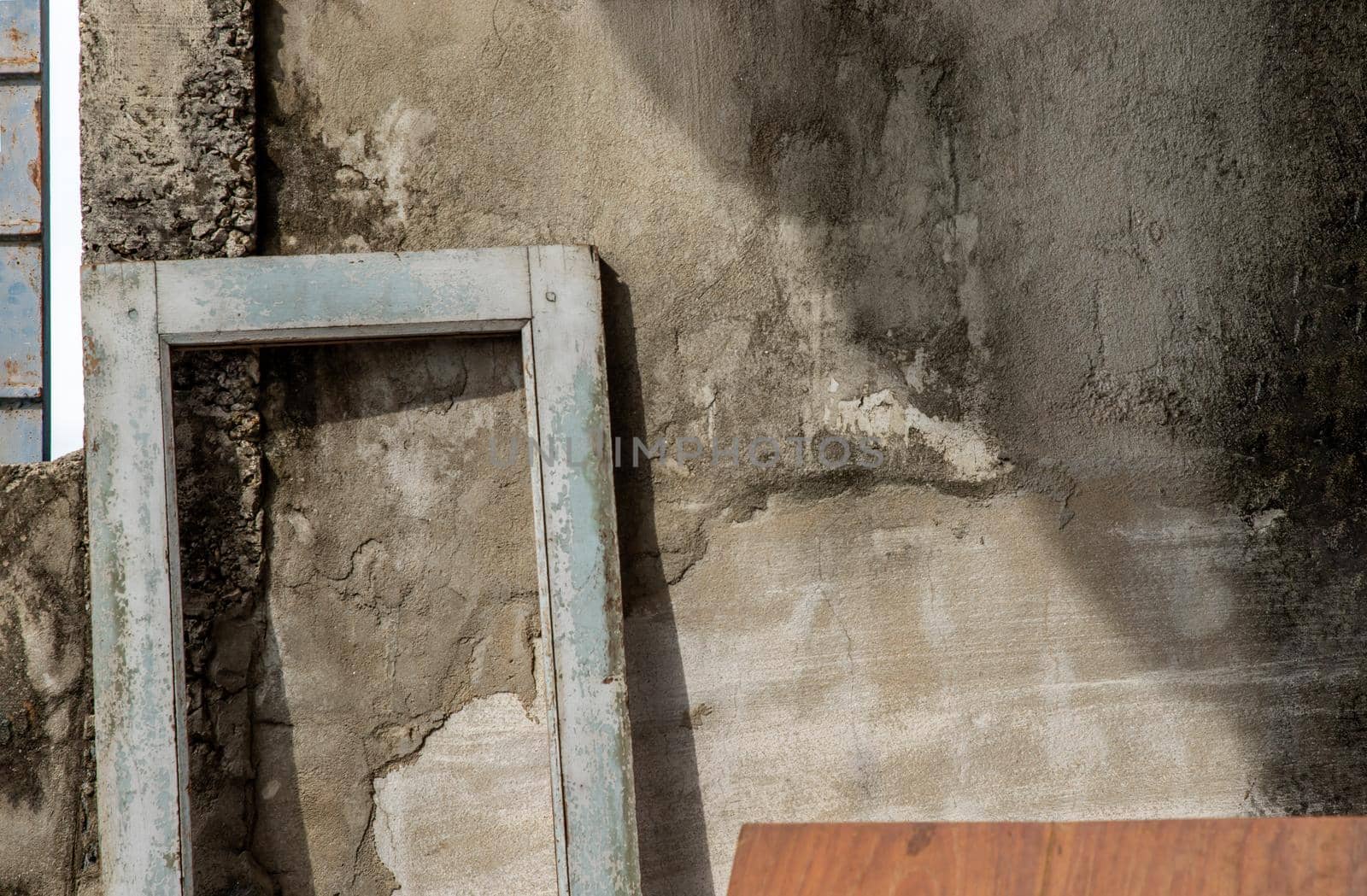 An old wooden door frame leaning on the background of an old concrete wall with cracks stands. space for your text, No focus, specifically.