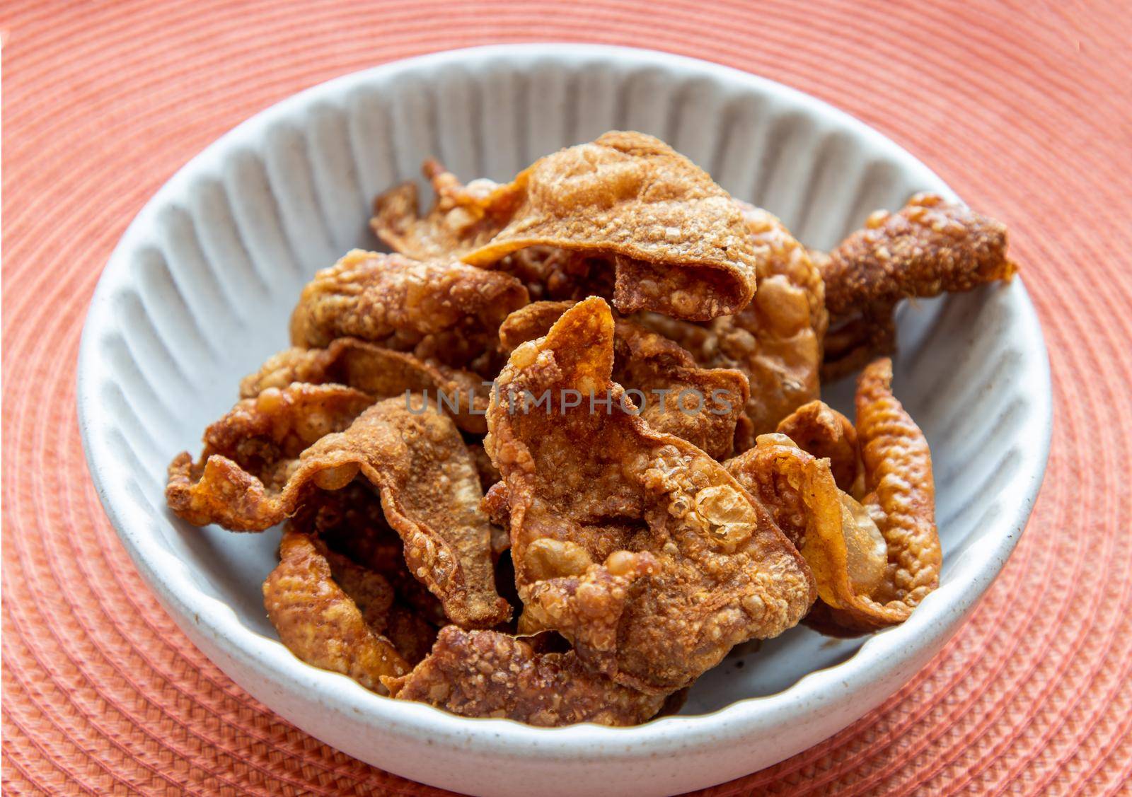 Thai Traditional Snacks, Crispy Fried Chicken skins in a white bowl on red background. Snack and Appetizers, copy space, No focus, specifically.