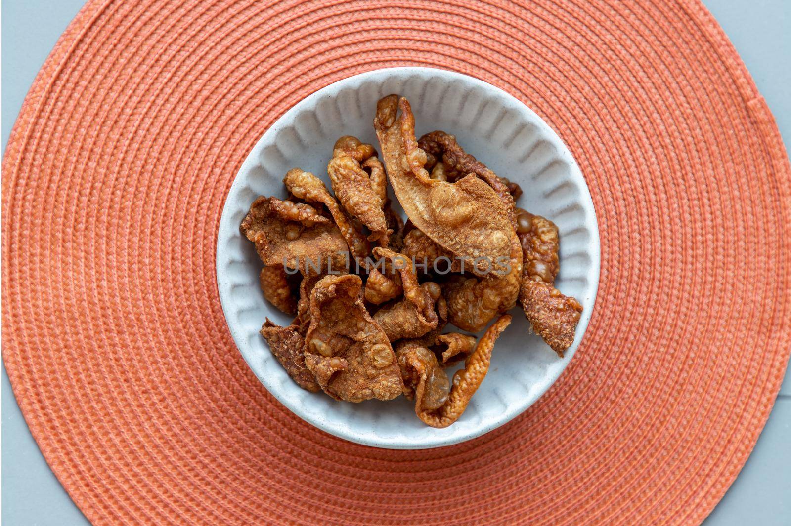 Thai Traditional Snacks, Crispy Fried Chicken skins in a white bowl on red background. Snack and Appetizers, copy space, No focus, specifically.