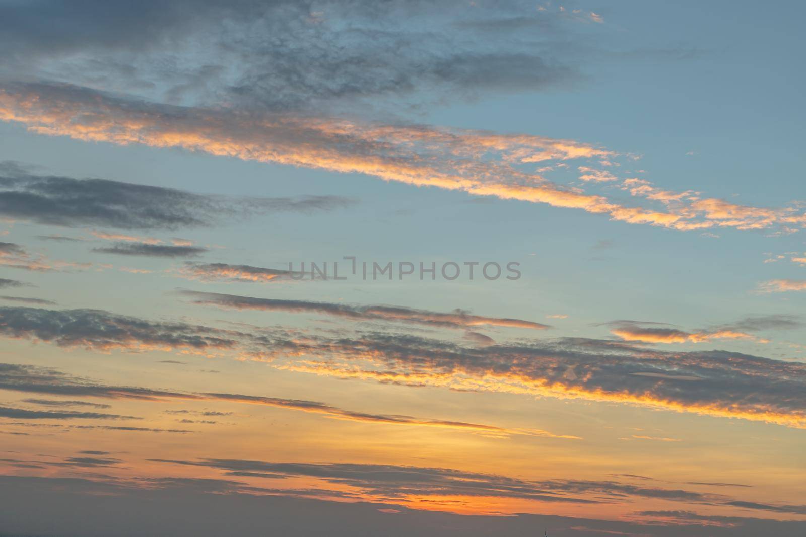 Scenic Colorful Sky At Sunset. Light blue clouds and orange on background, The softness of the cloud creates a feeling of relaxation. Copy space. No focus, specifically.