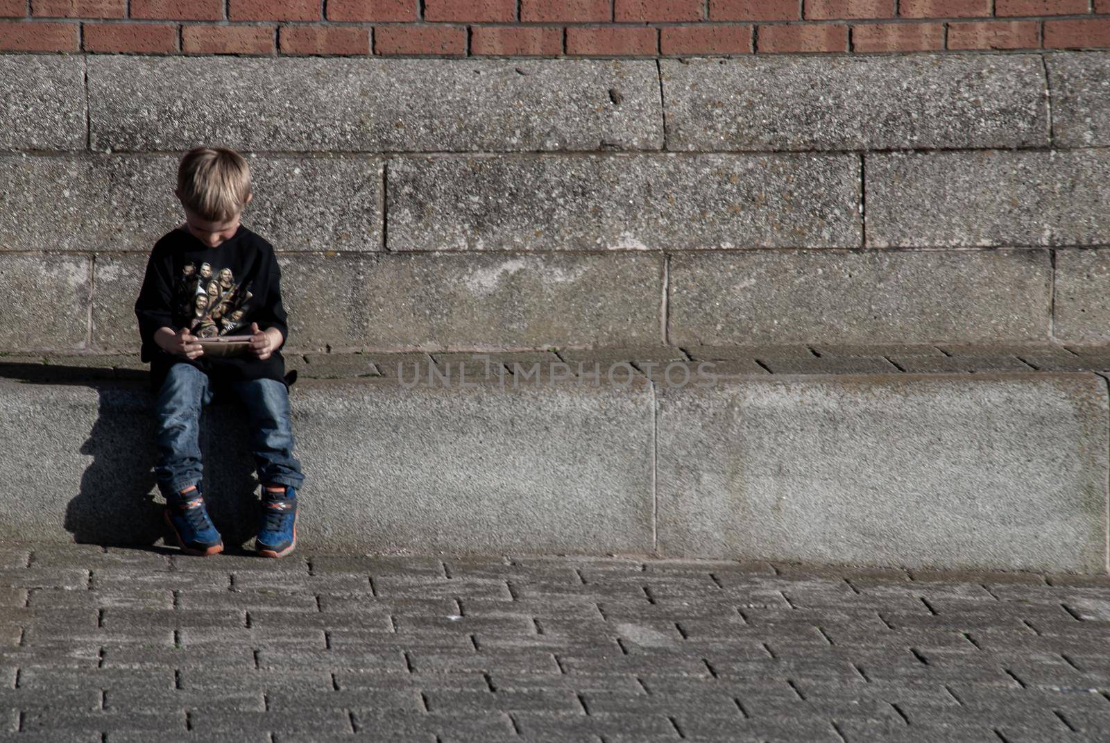 Liverpool, United Kingdom - 03 Jan 2019 : Child sitting on the aisle and watching something on Ipod in the aisle at River Mersey, Royal Albert Dock. Copy space, Focus and blur.