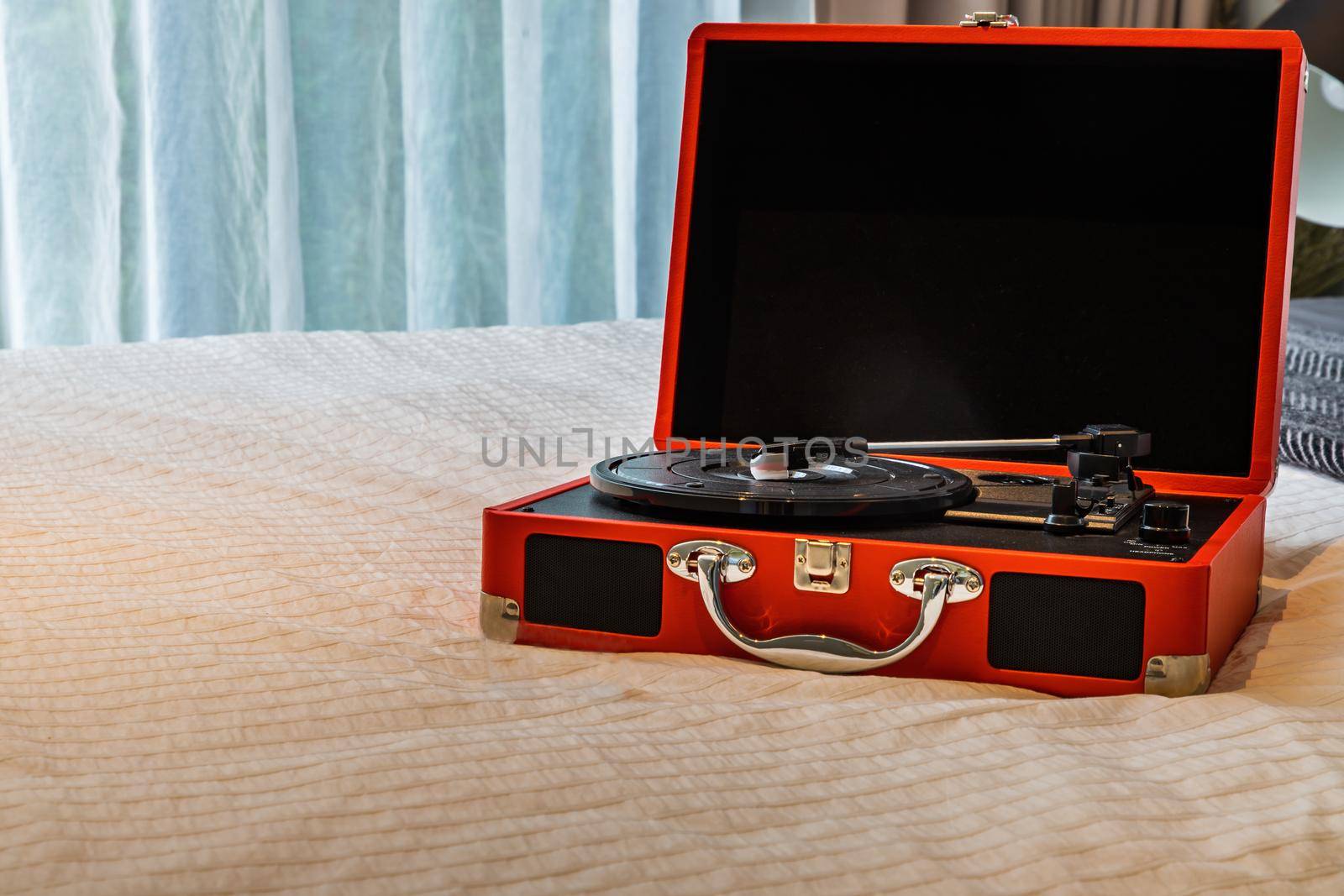 Portable turntable on white bed in bedroom. Selective focus.
