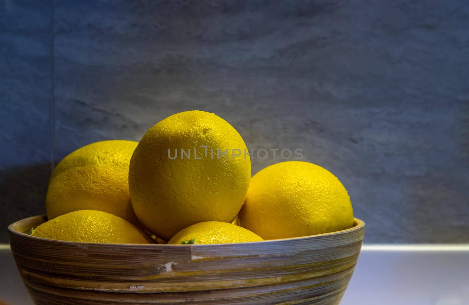 Lemons in a wooden bowl on on a kitchen table. Selective focus.